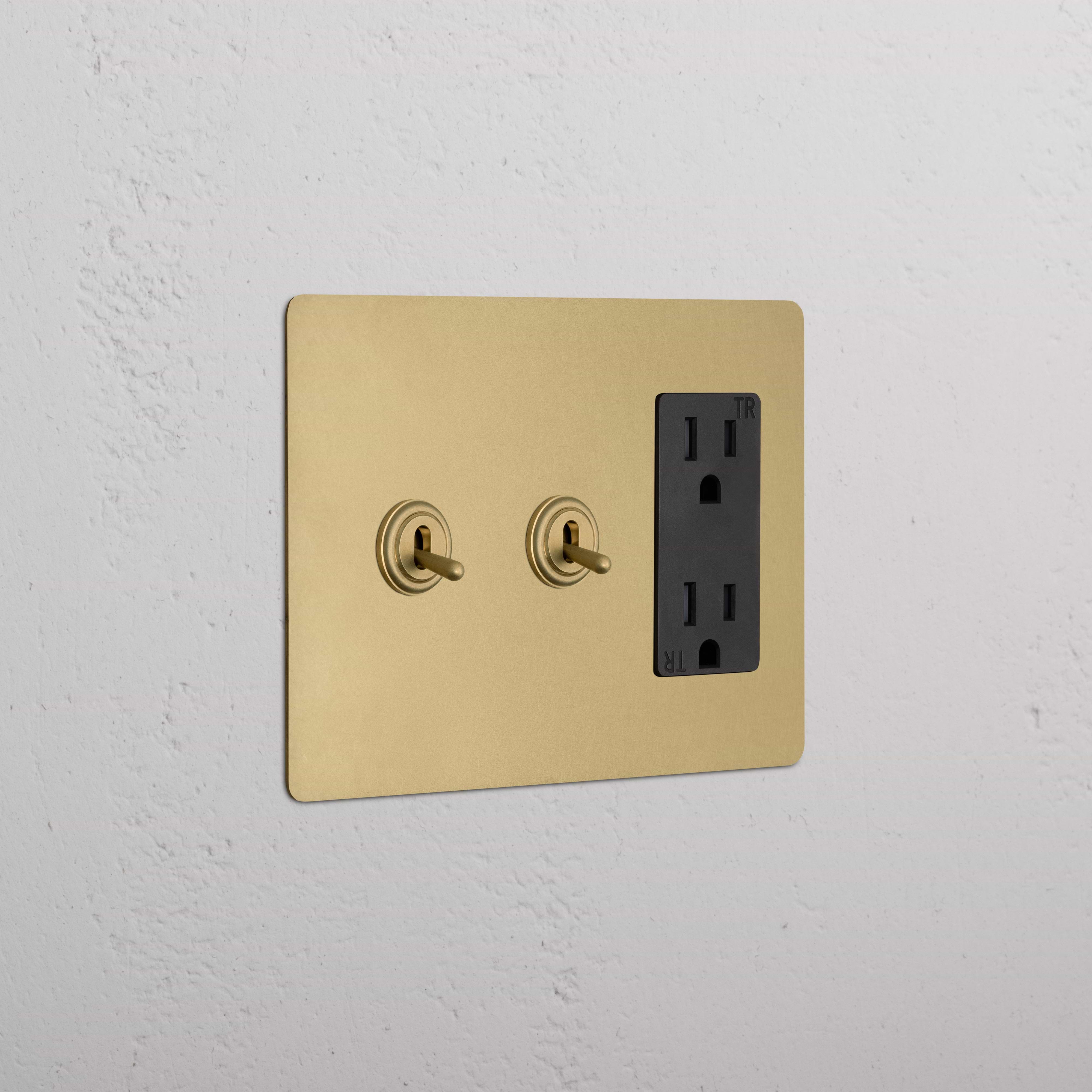 Kew 3G 2x Toggle Switch & Outlet in Antique Brass Black with two toggles and black outlet on wall plate.