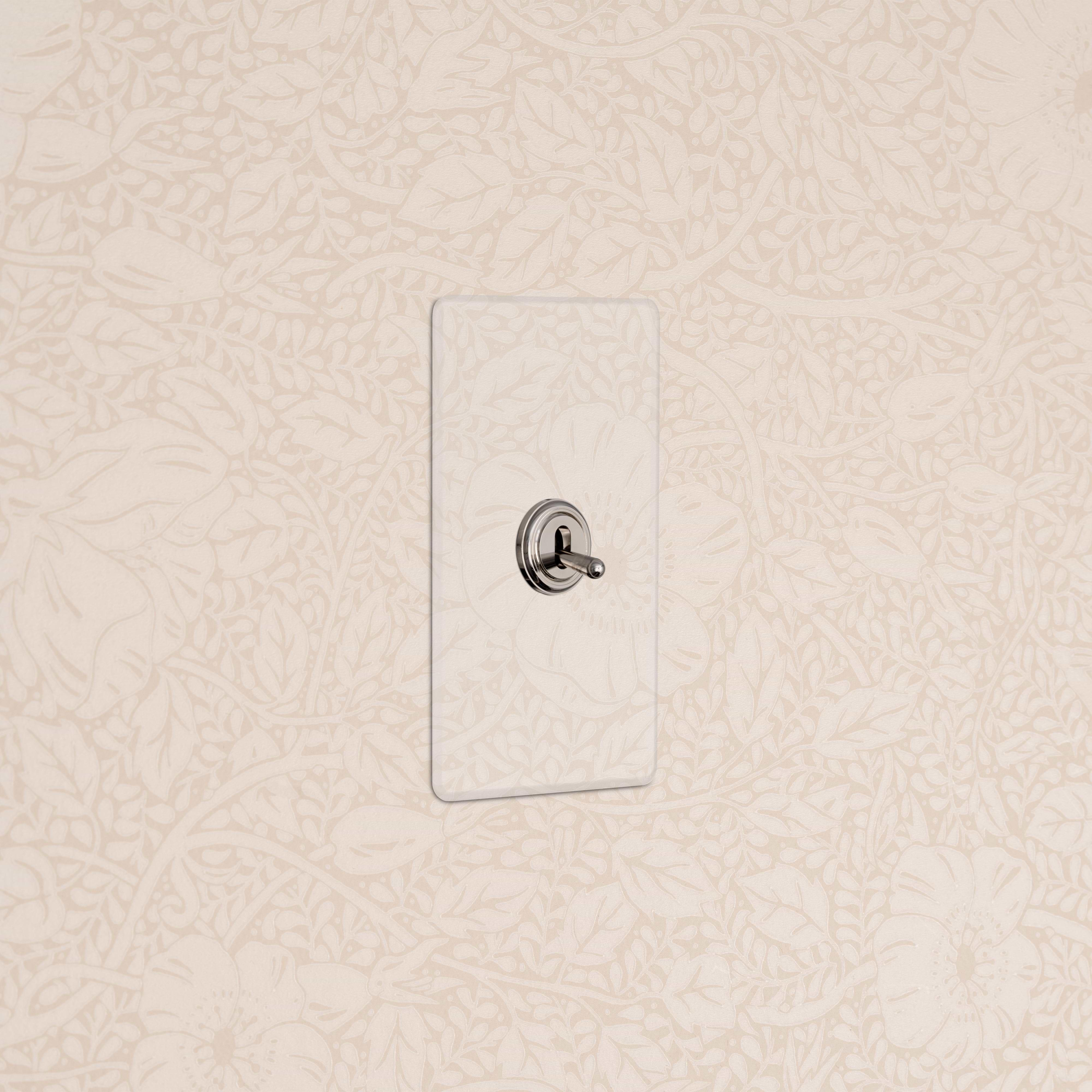 Kew 1G Retractive Toggle Switch in Clear Polished Nickel, installed on floral-patterned cream wallpapered wall.