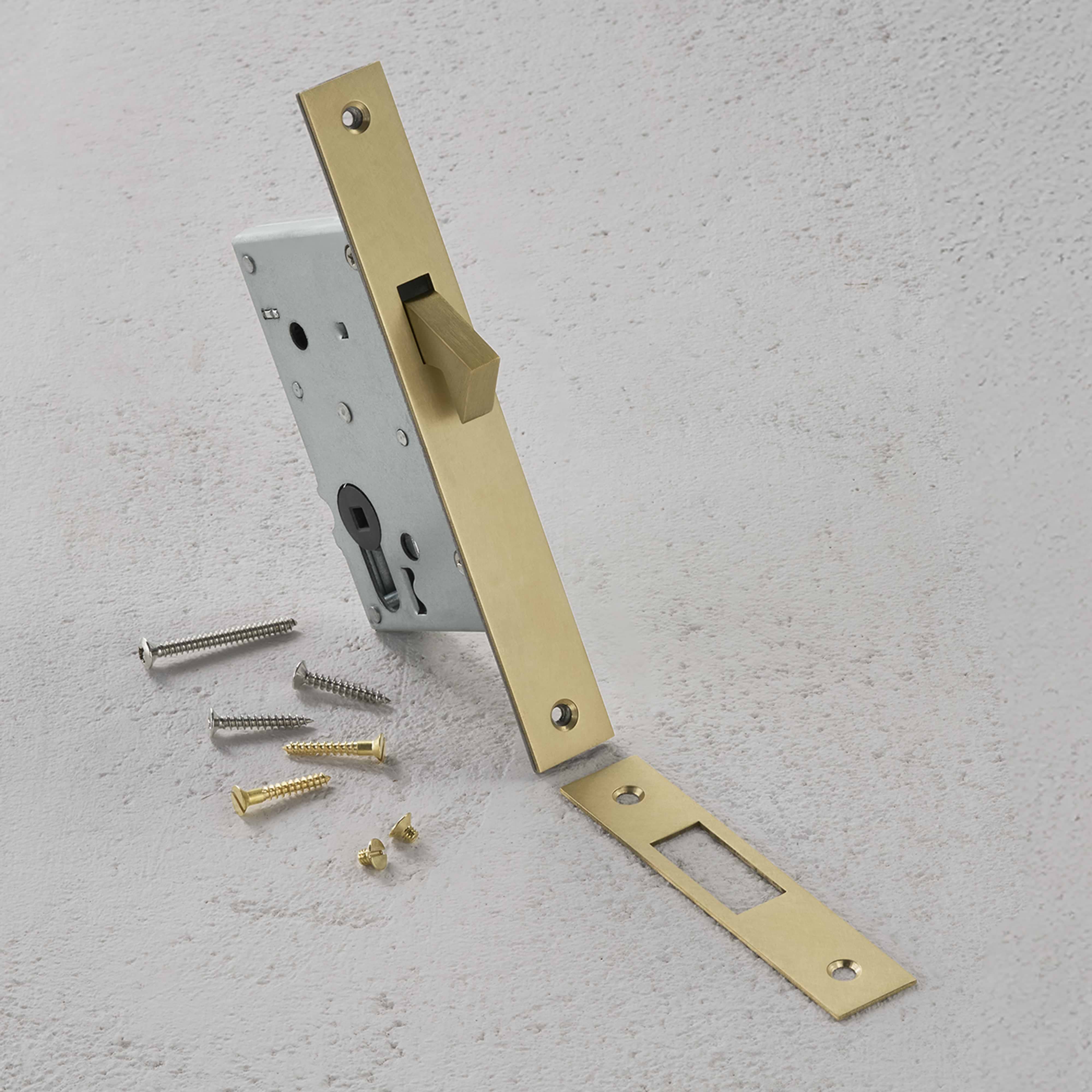 Antique brass hook lock with matching strike plate and six screws, shown on a light textured surface.