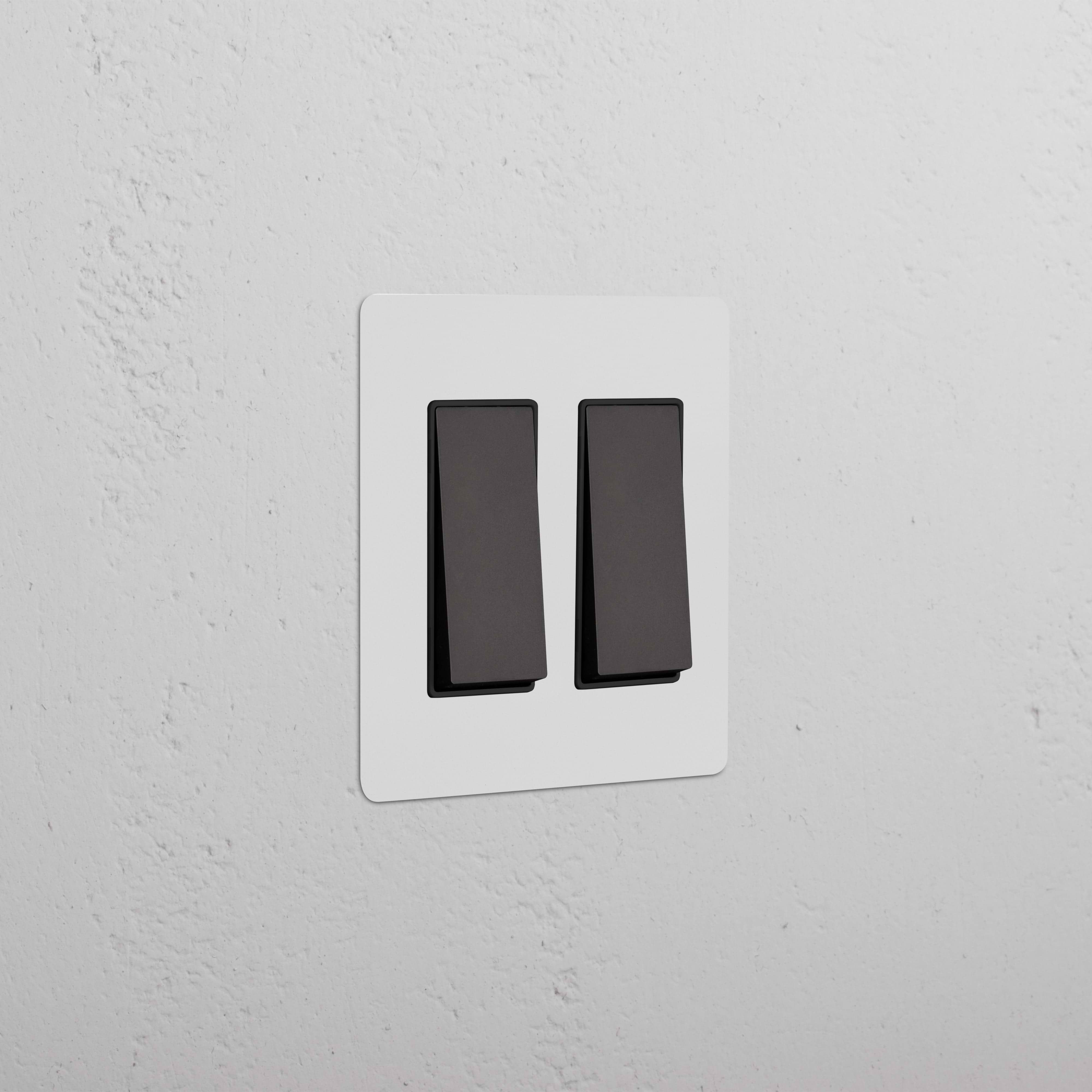Kew 2G Rocker Switch in paintable bronze black finish, shown mounted on a white wall.