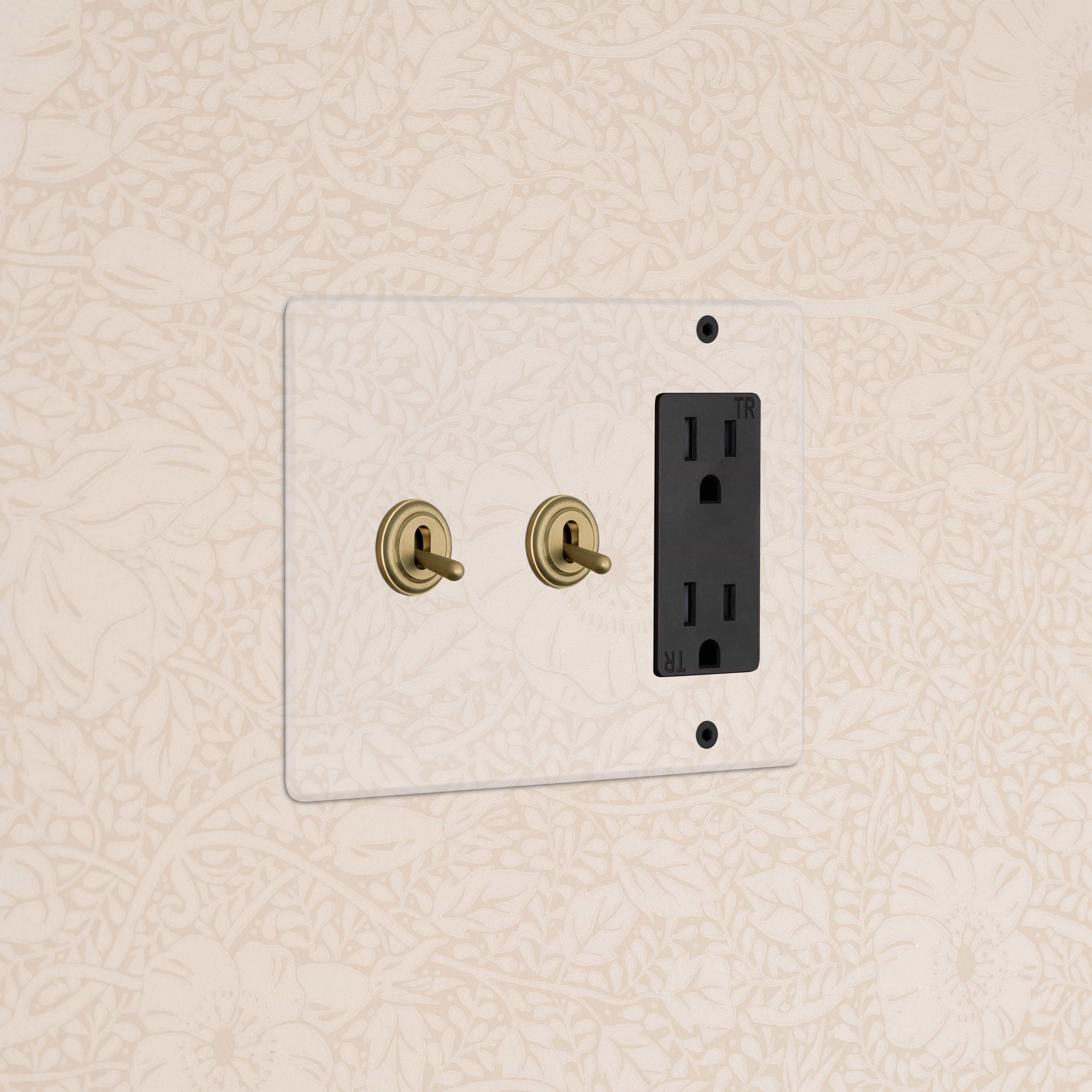 Kew 3G 2x Toggle Switch & Outlet in clear antique brass black, double toggle and outlet on wall.
