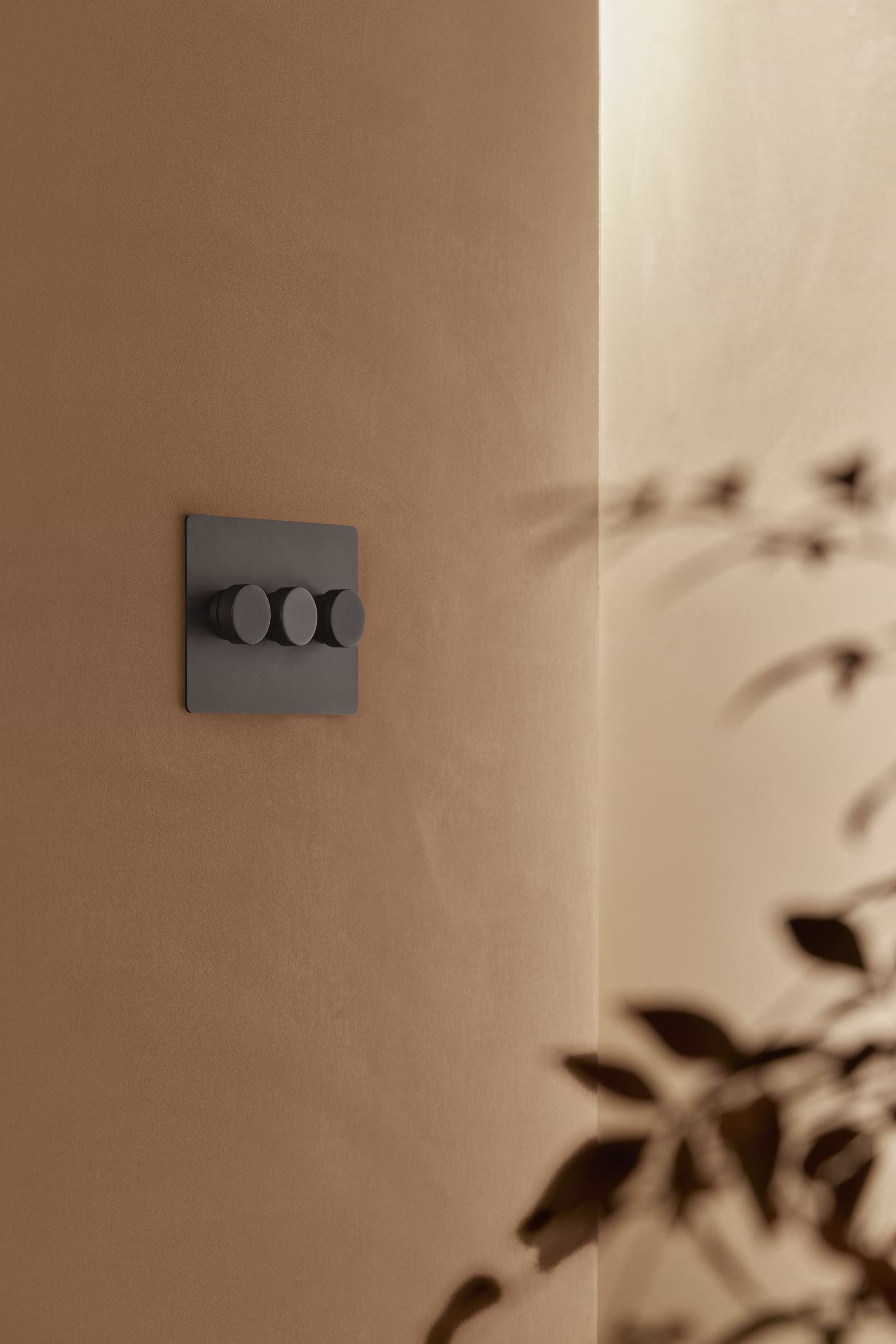 Kew 3G Dimmer Switch in bronze finish with three rotary knobs mounted on a wall.