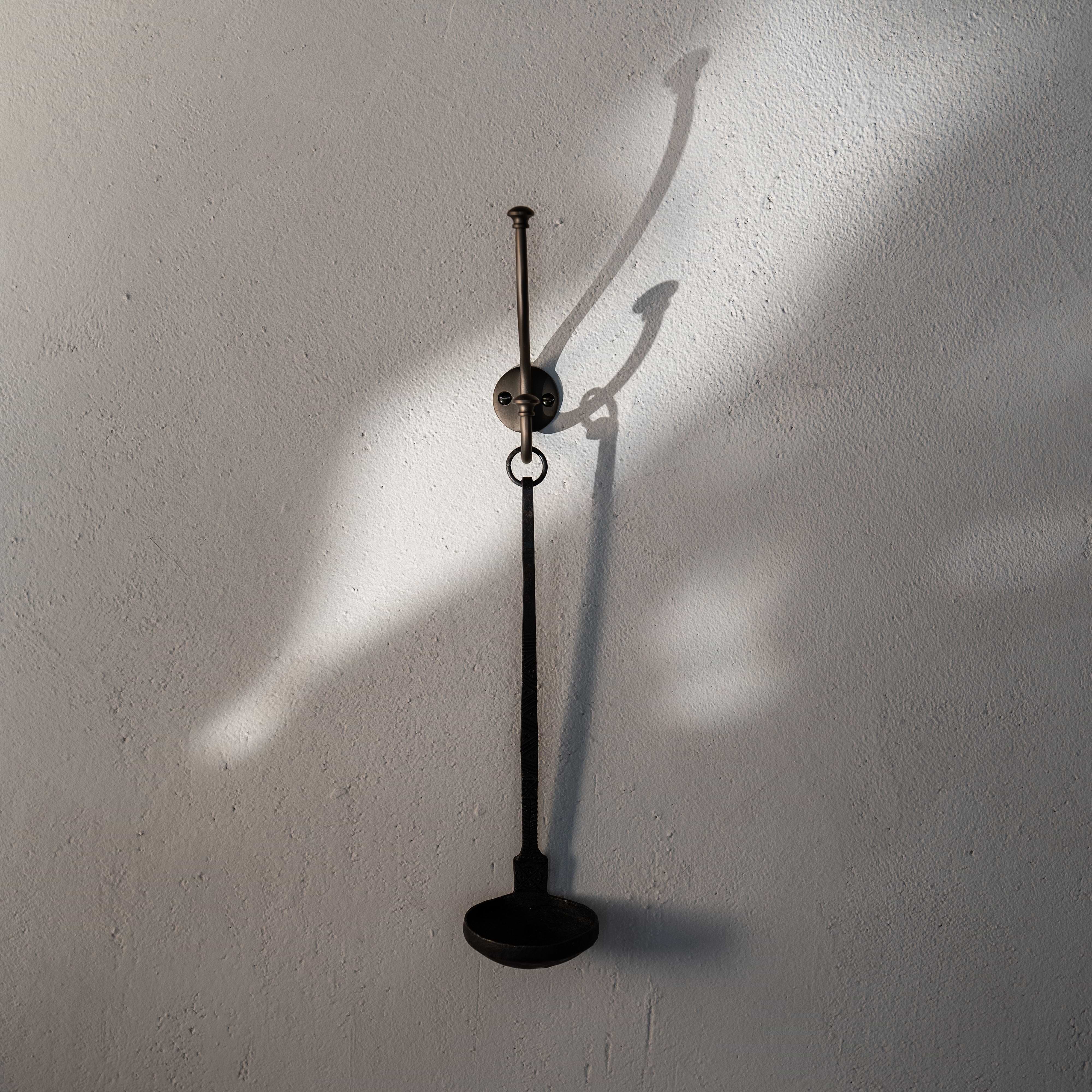 Bronze Mews Hook mounted on a white textured wall, displaying its sleek, functional design.