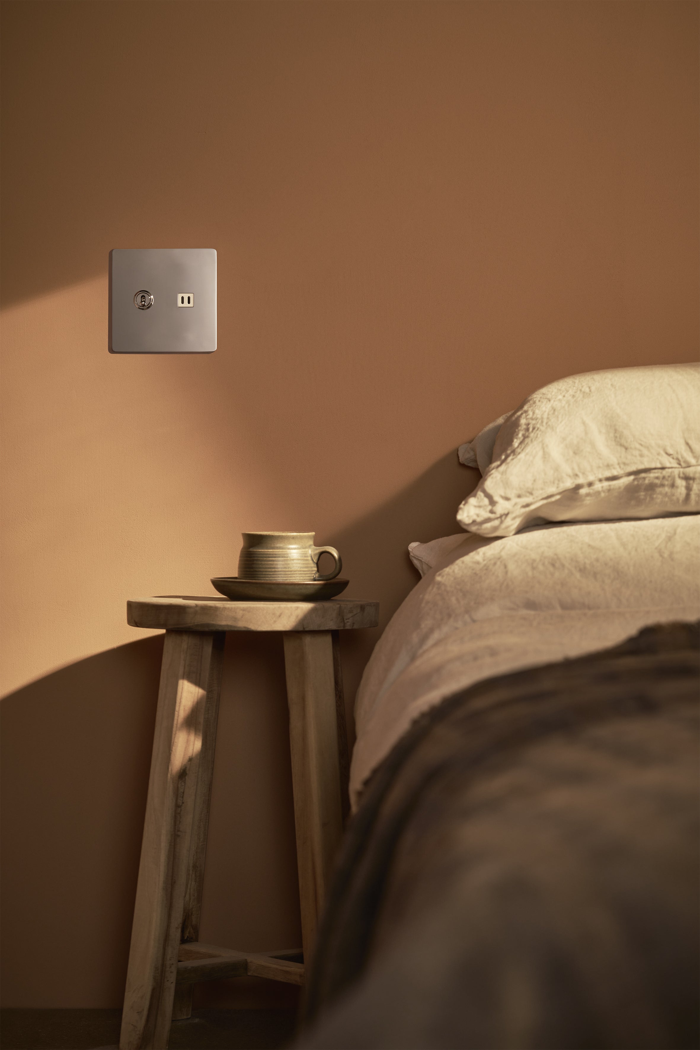 Kew 2G Toggle Switch & Fast Charge USB outlet in polished nickel white, mounted on a light wall above a side table.