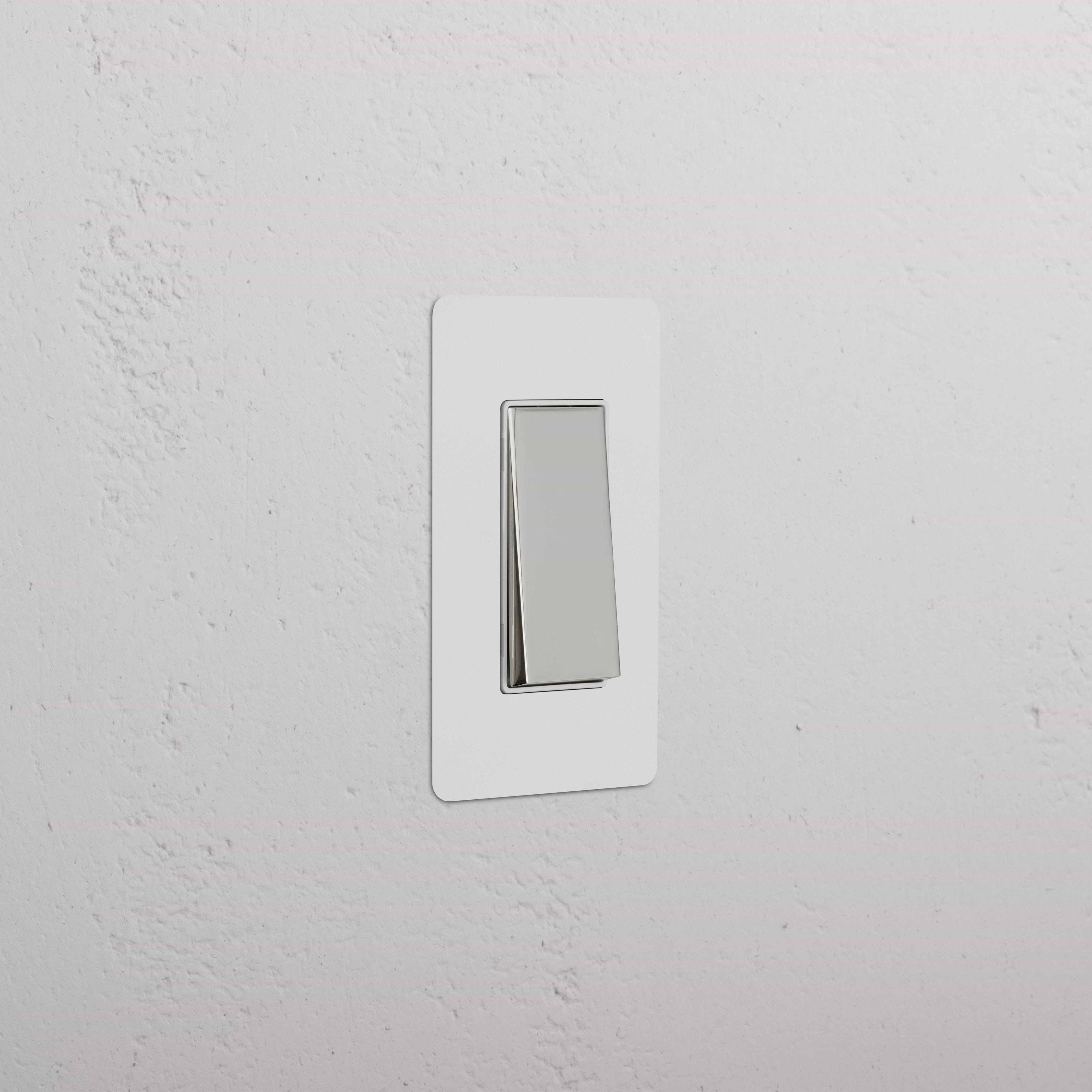 Kew 1G Rocker Switch with paintable polished nickel white plate, shown mounted on a white wall.