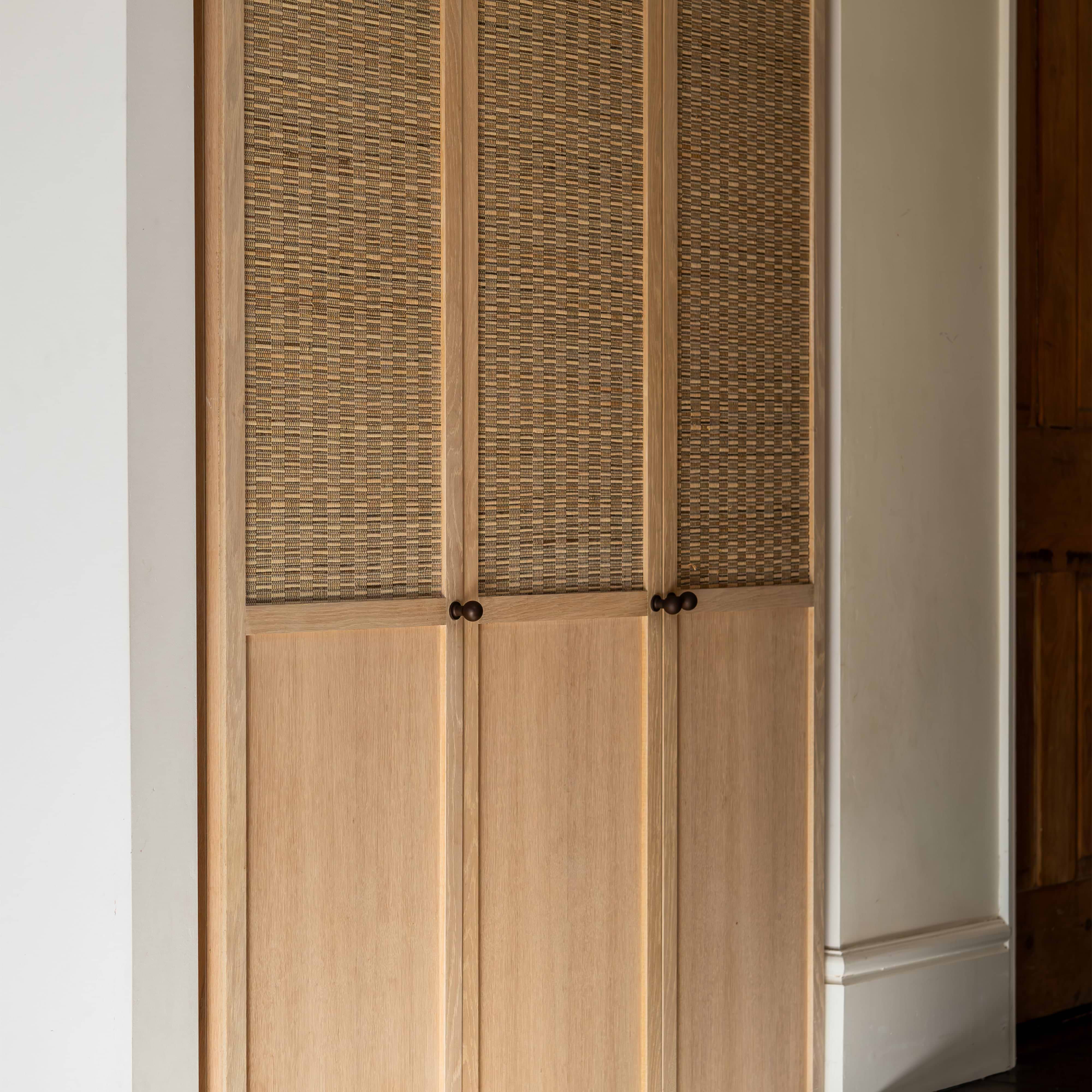 Close-up of Bayswater Furniture Knob Small in bronze finish attached to a cabinet door.