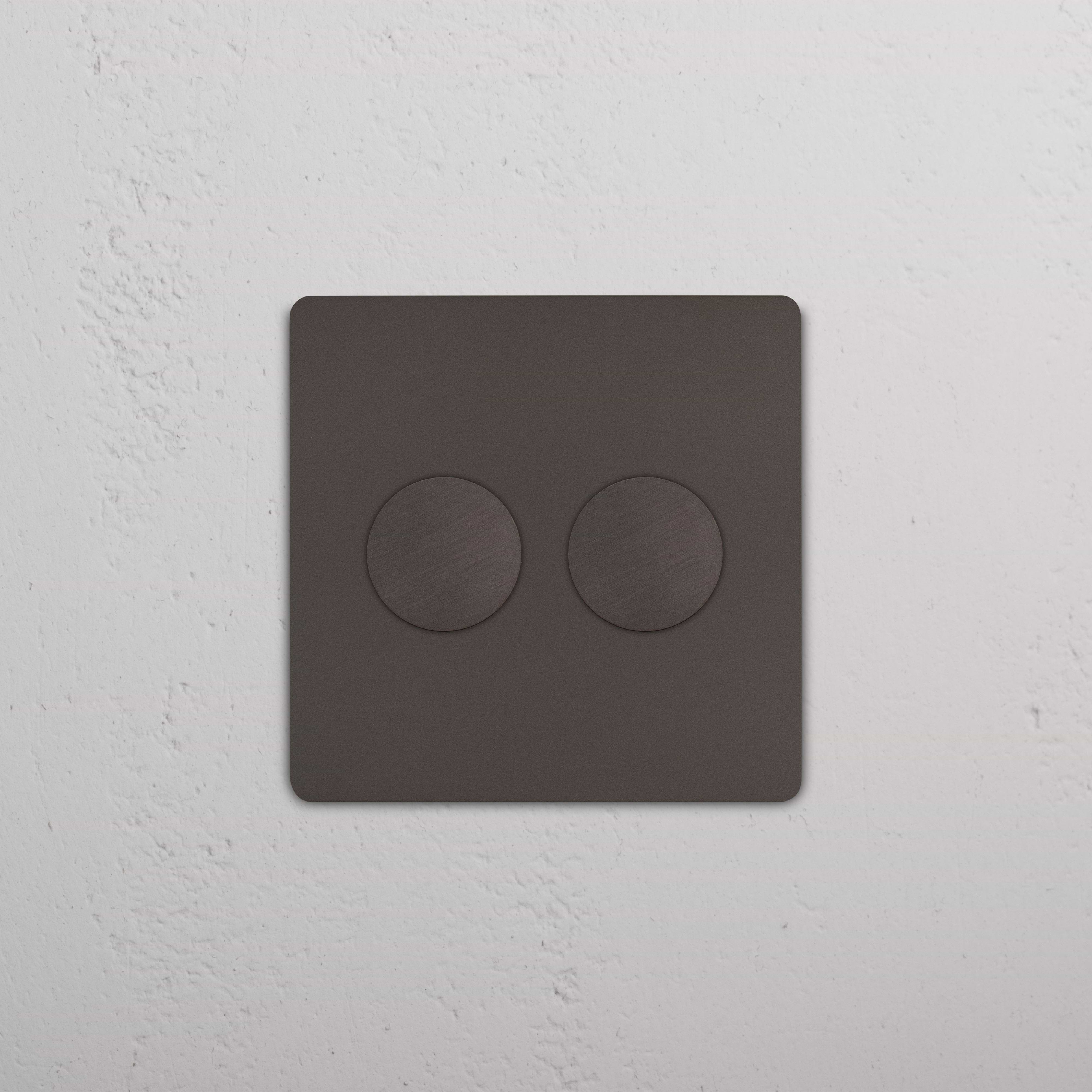 Bronze Grove 2G Dimmer Switch with two round dials, mounted on a white textured wall.