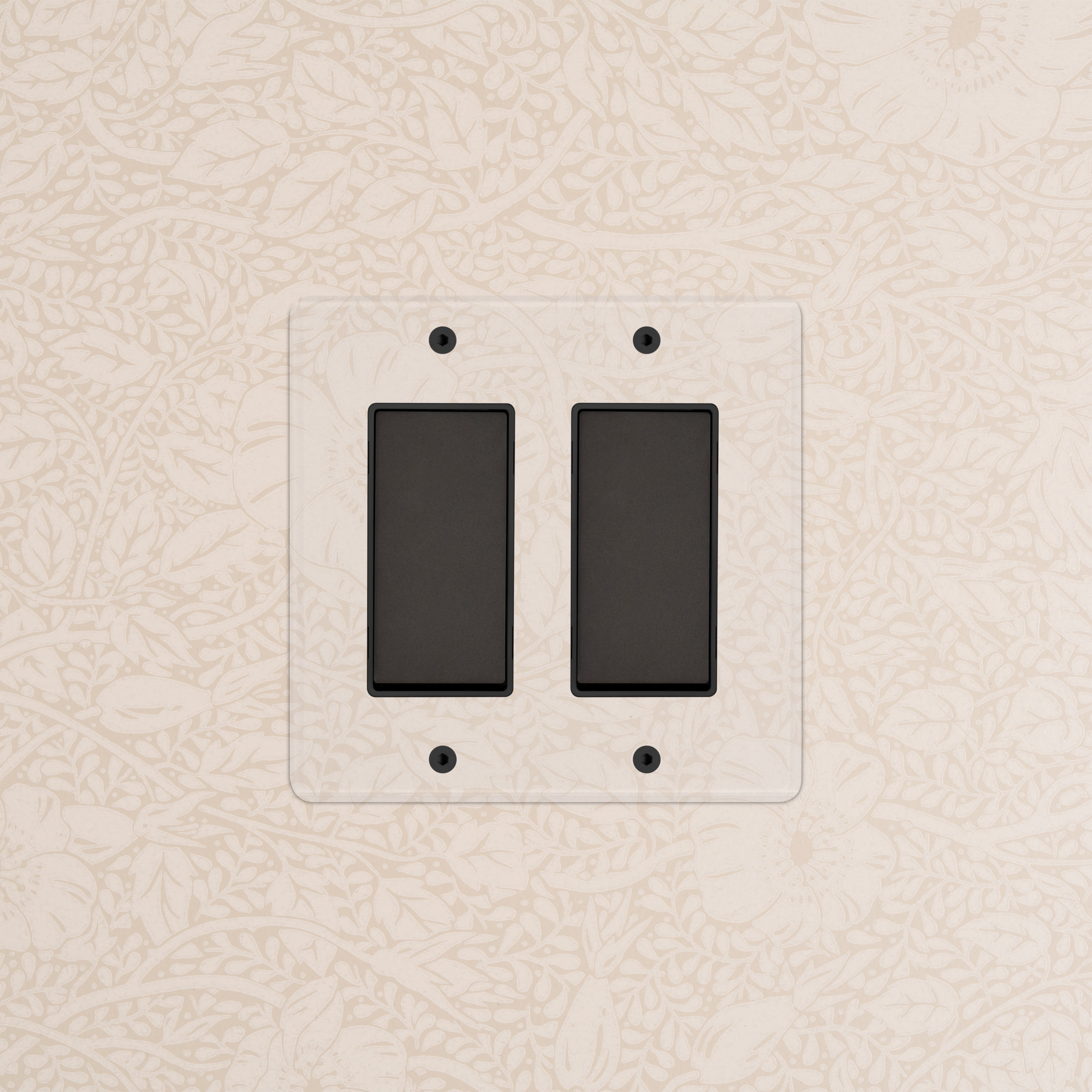 Kew 2G Rocker Switch with black switches and a clear bronze black plate mounted on floral wallpapered wall.