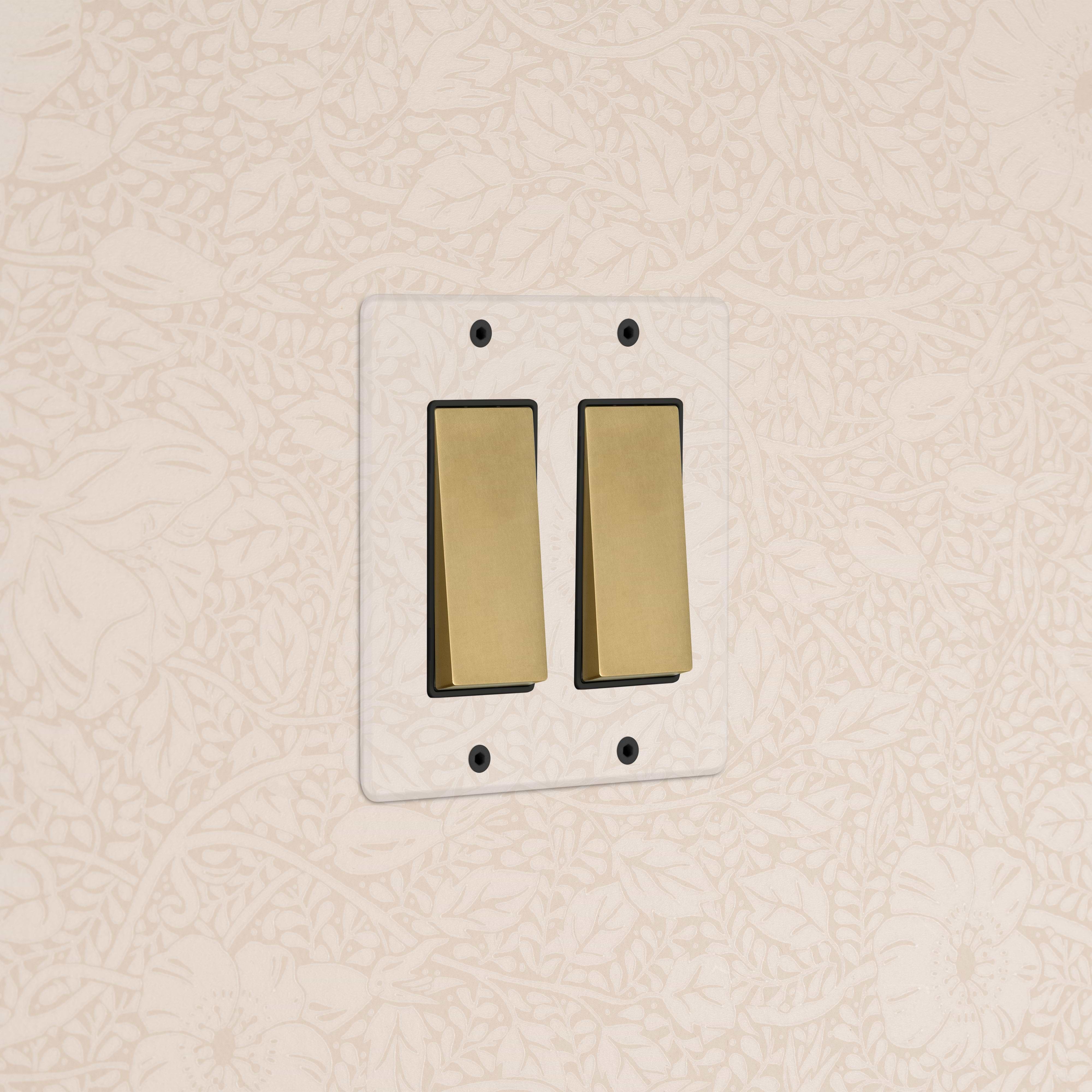 Kew 2G Rocker Switch in clear antique brass with black detail, shown mounted on a wall.