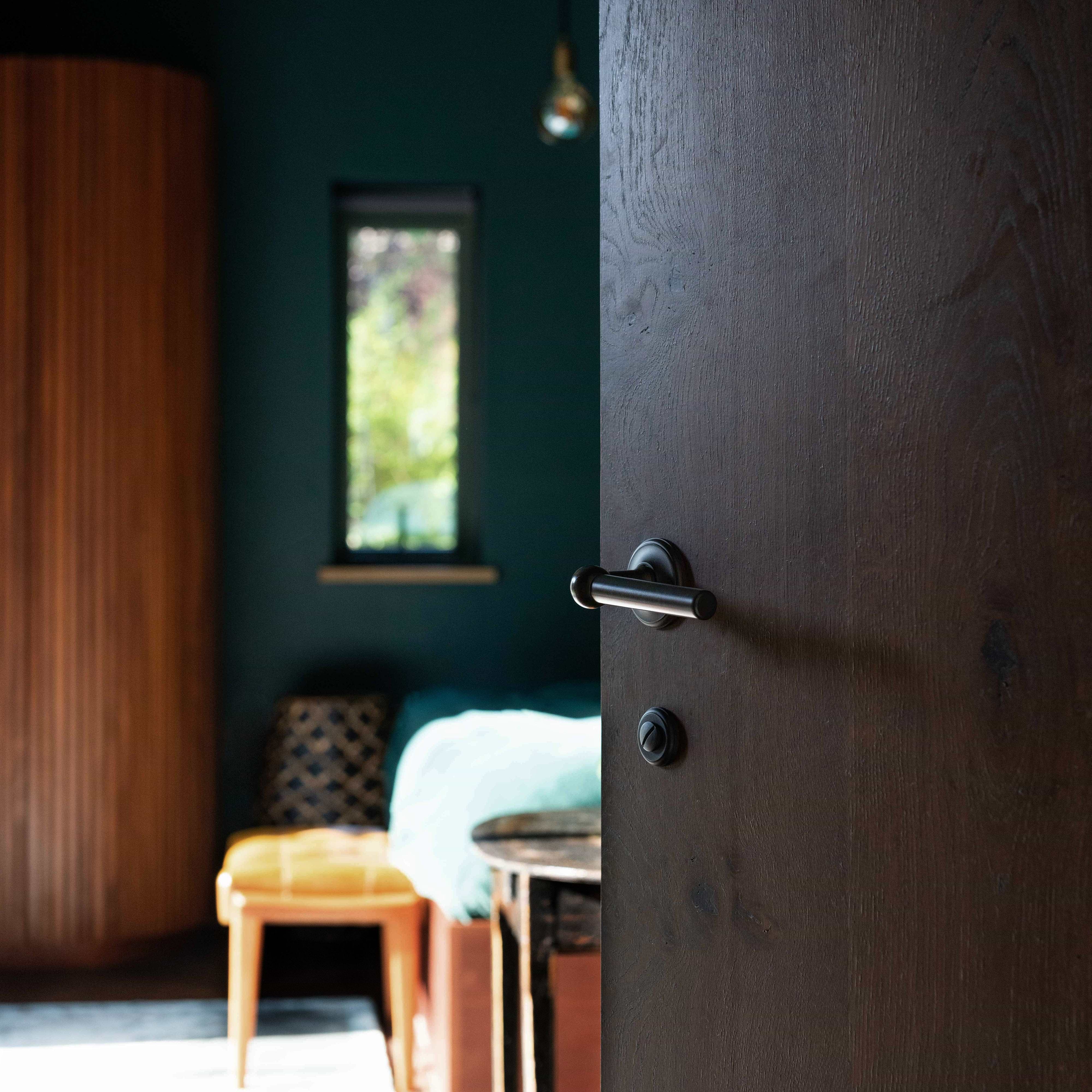 Bronze Harper Passage Door Handle Set installed on a dark wooden door, showing handle detail and finish.