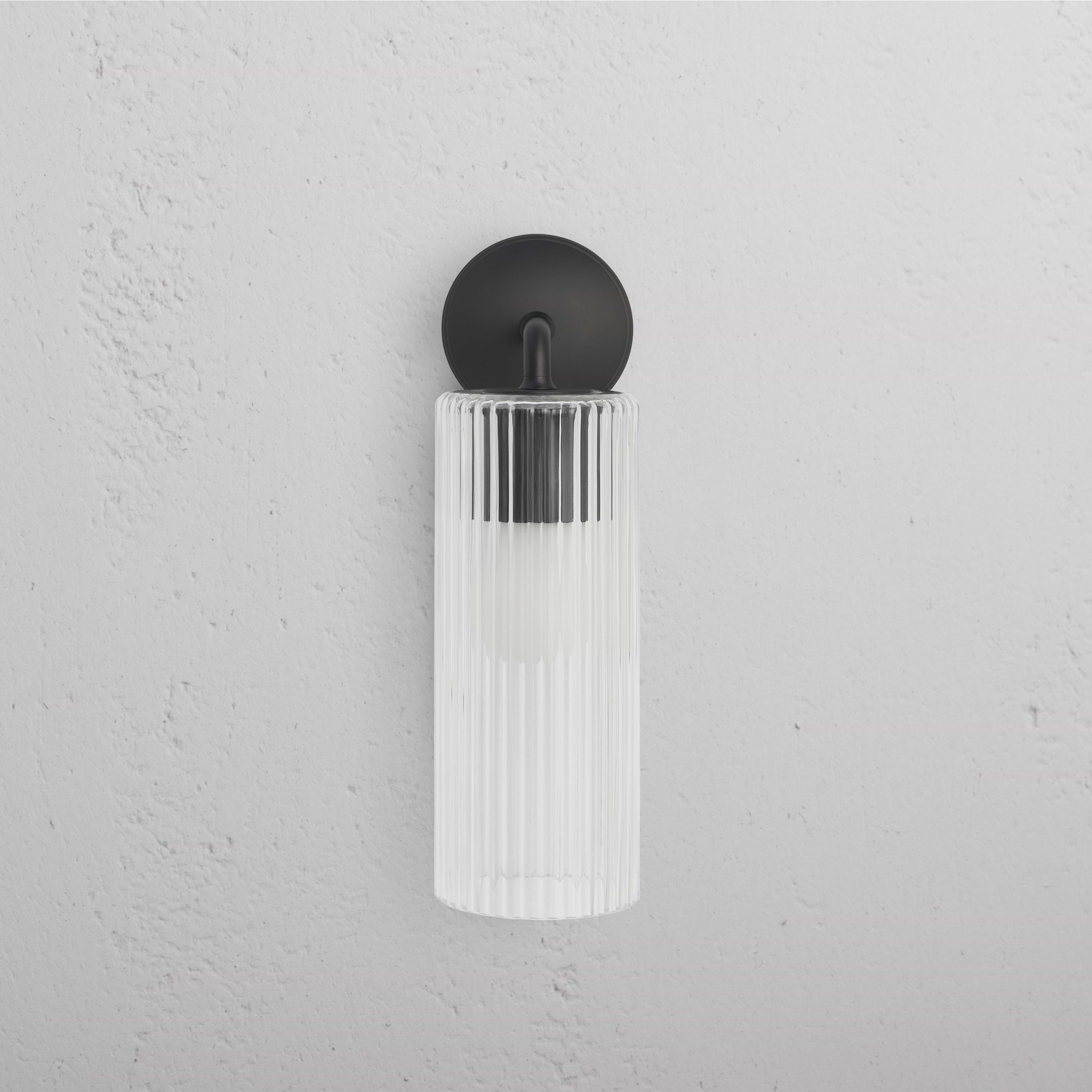 Large Claremont Wall Light in bronze with vertically fluted glass shade, mounted on a white wall.