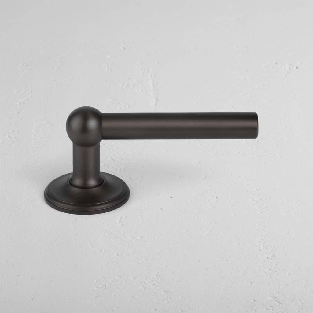 Bronze Harper Dummy Door Handle Set with a round base, shown mounted on a white textured surface.