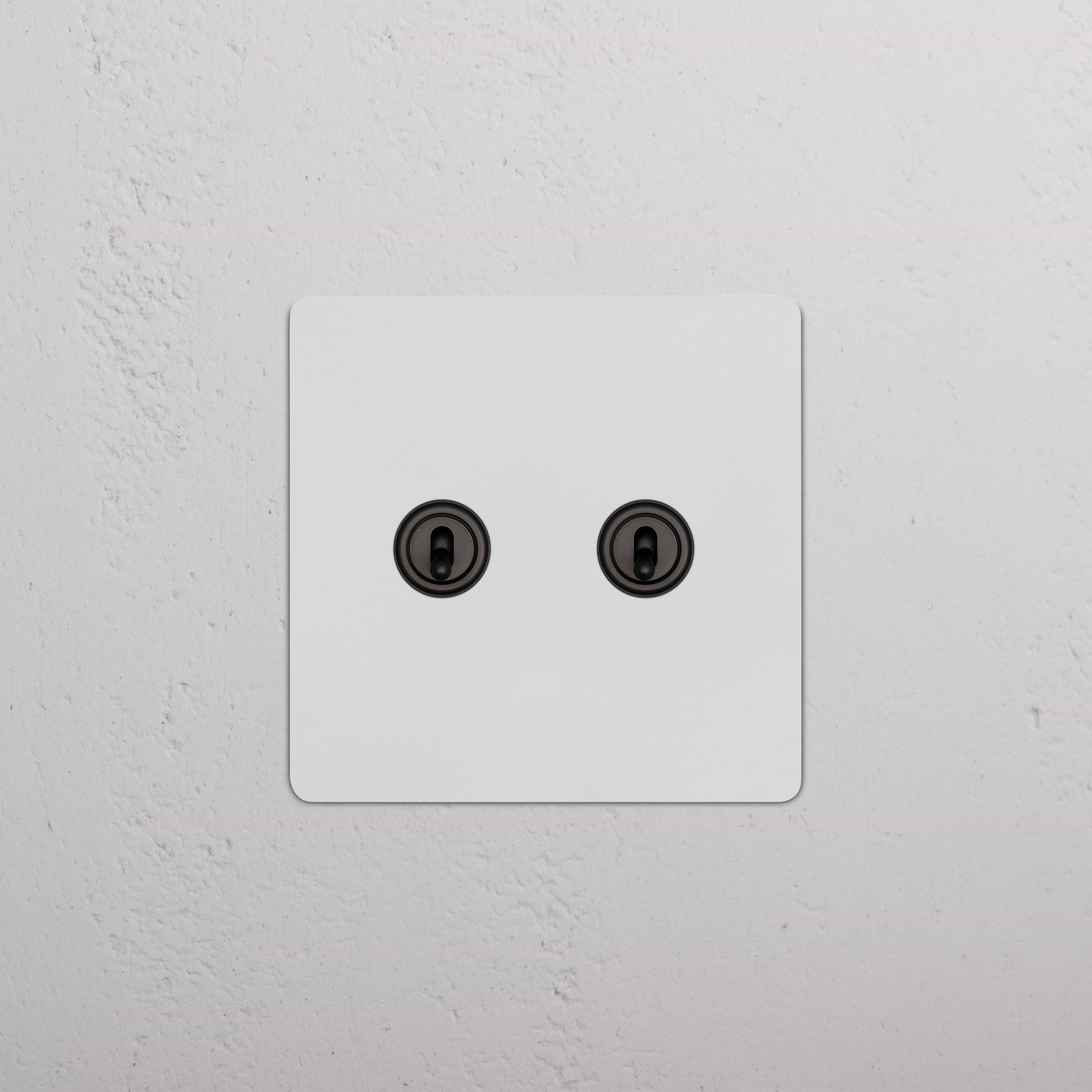 Kew 2G Toggle Switch in paintable bronze finish, featuring two toggle switches on a square faceplate.