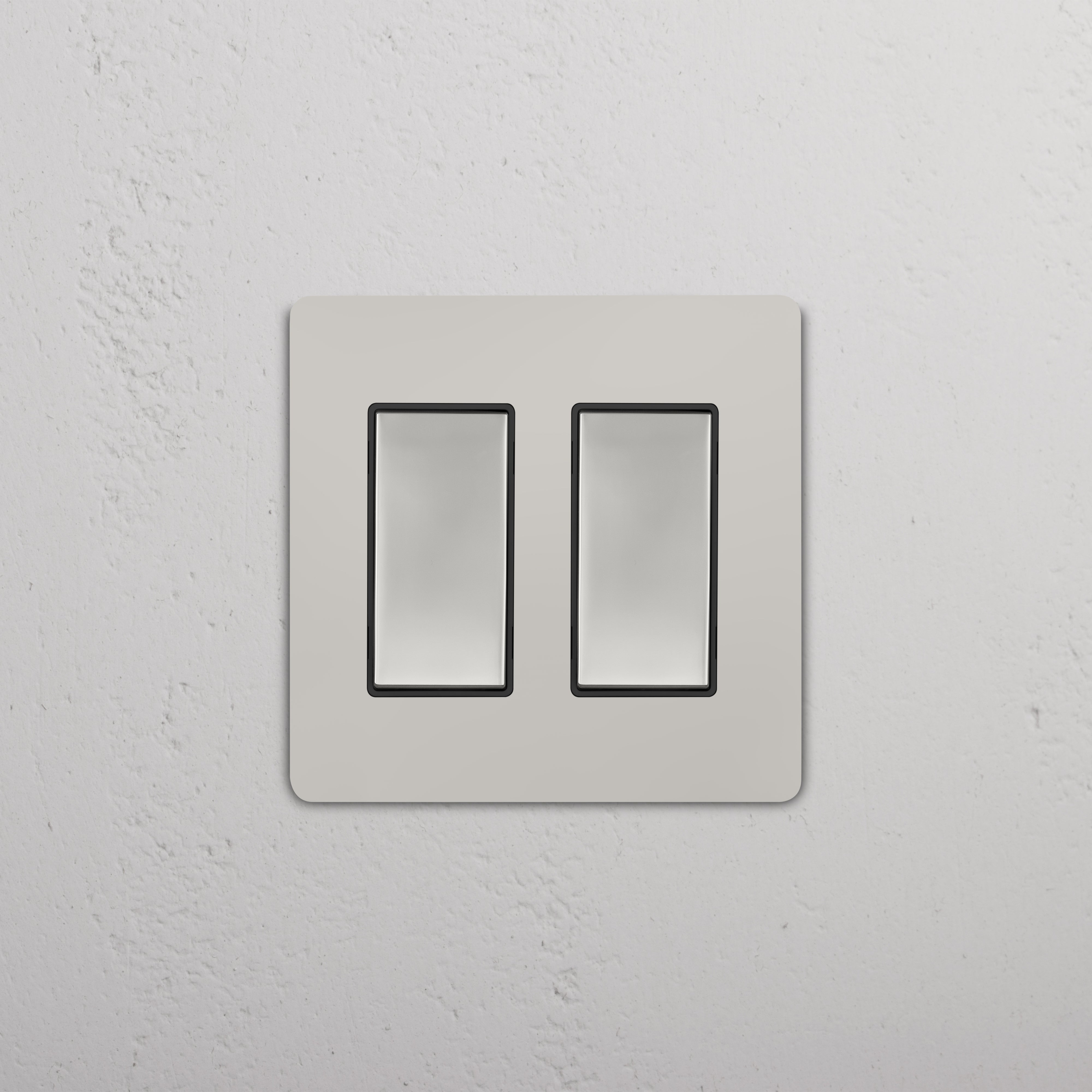 Grove 2G Rocker Switch in polished nickel black, double rectangular switches on a textured white wall.