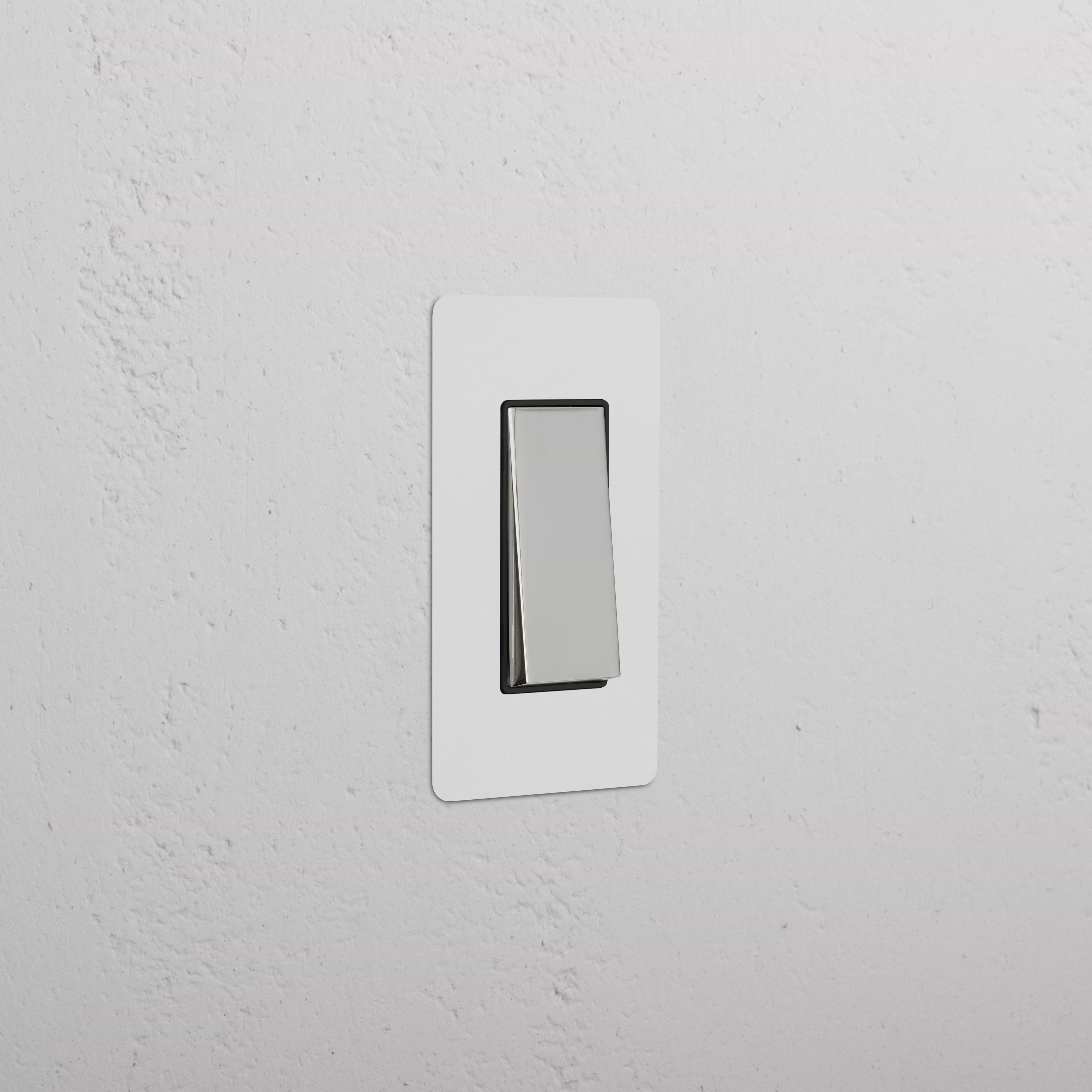 Kew 1G Retractive Rocker Switch in paintable polished nickel black finish, mounted on a white wall.