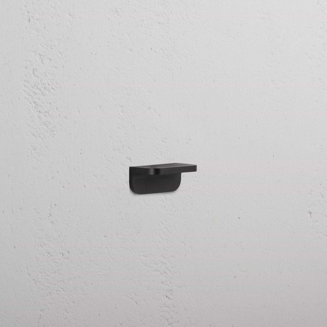 Oxford Furniture Handle Extra Small in bronze with a minimalist, rounded design mounted on a white wall.