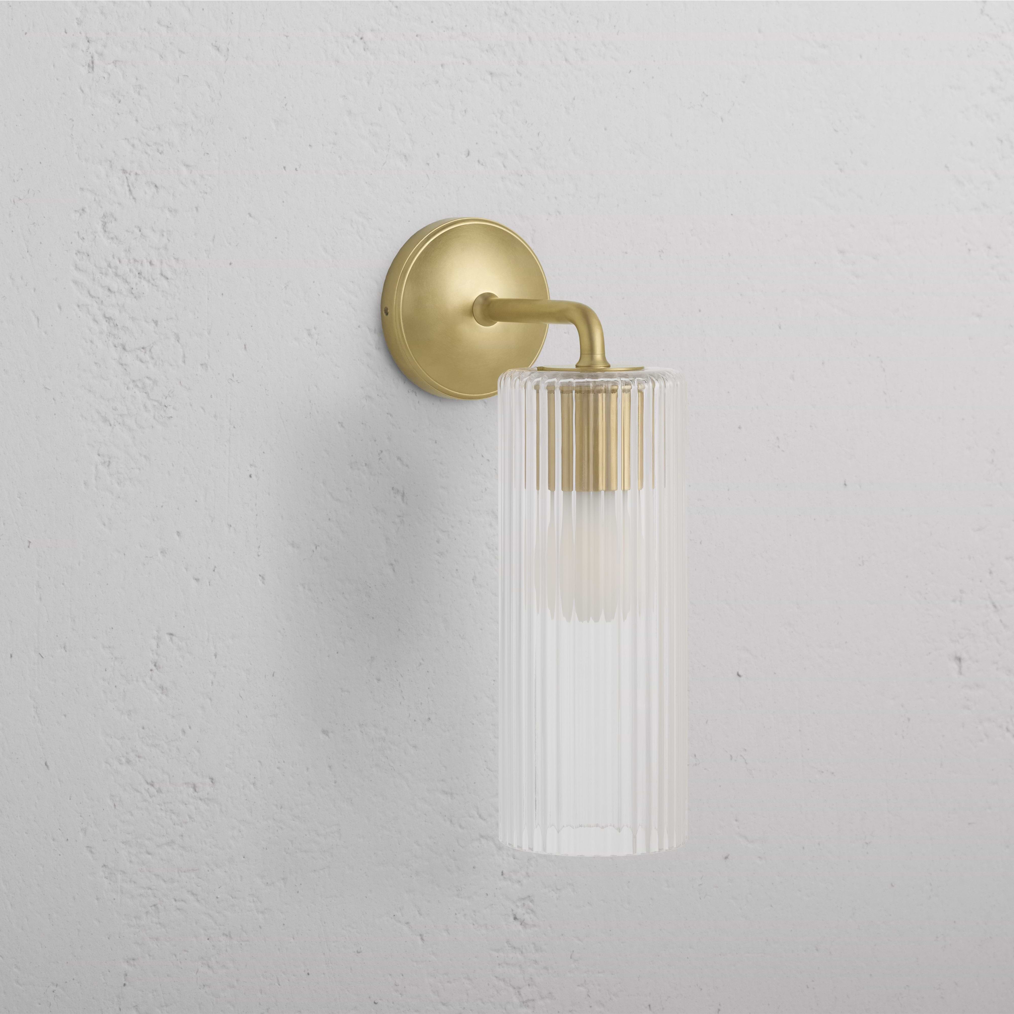 Large Claremont Wall Light with fluted glass shade and antique brass base, mounted on a white wall.