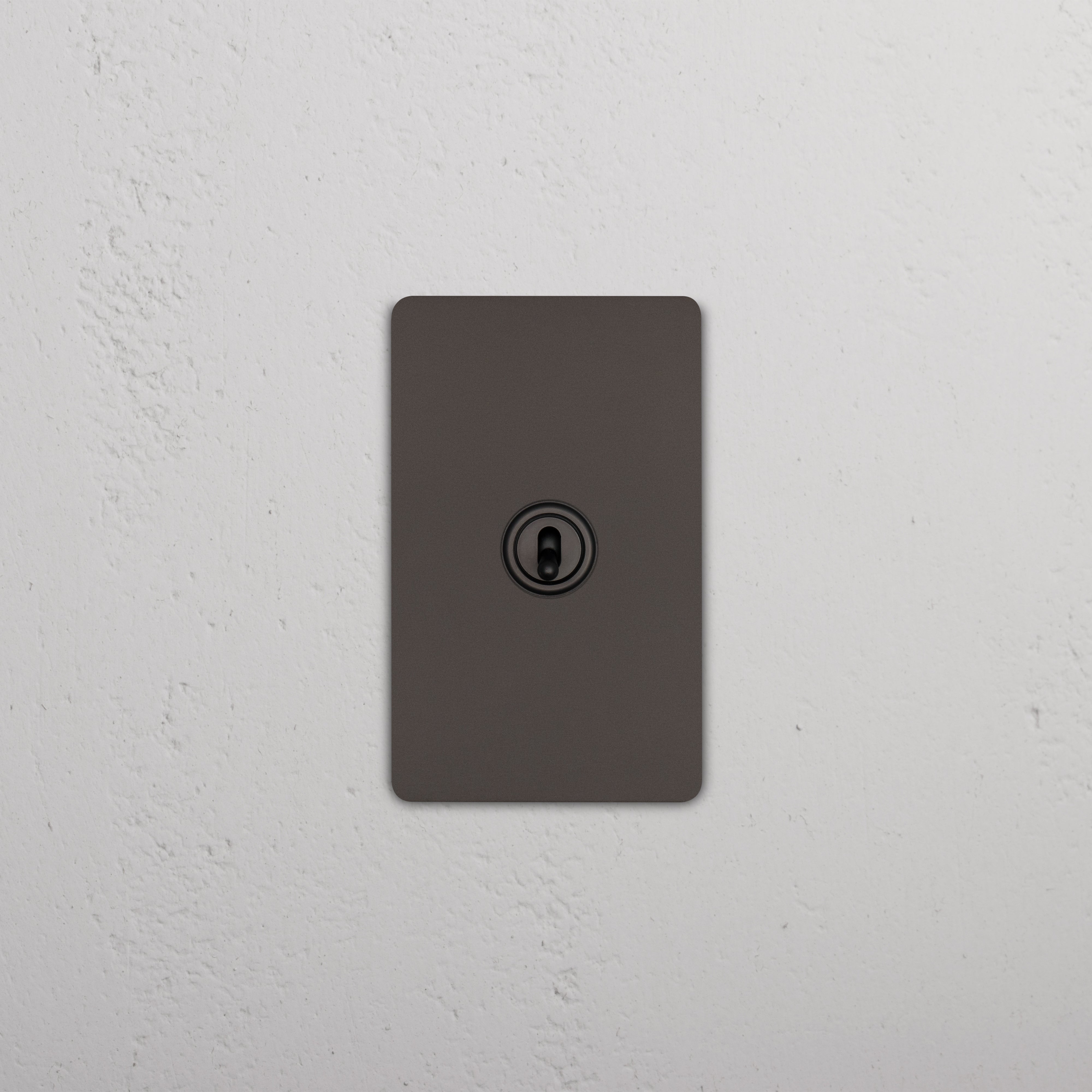 Bronze Grove 1G Retractive Toggle Switch with a central toggle on a rectangular wall plate, mounted on a white wall.