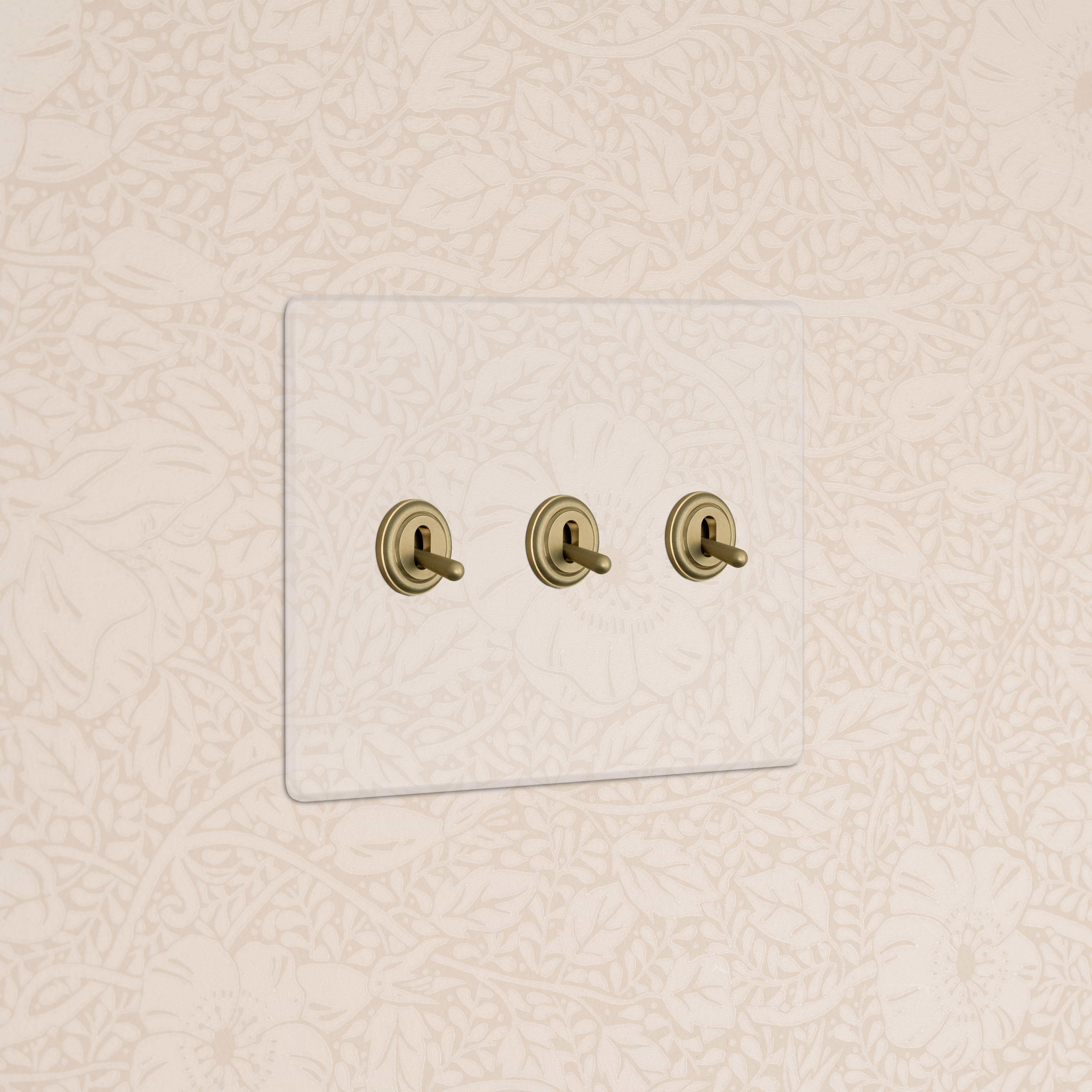 Kew 3G Toggle Switch in Clear Antique Brass with three horizontal toggles on a clear switch plate.