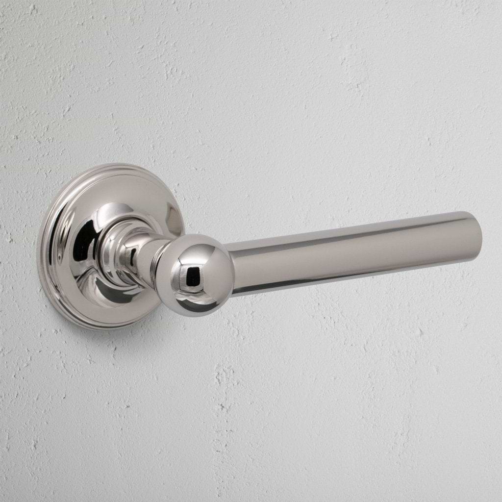 Harper Dummy Door Handle Set in polished nickel with round base, shown mounted on a white wall.