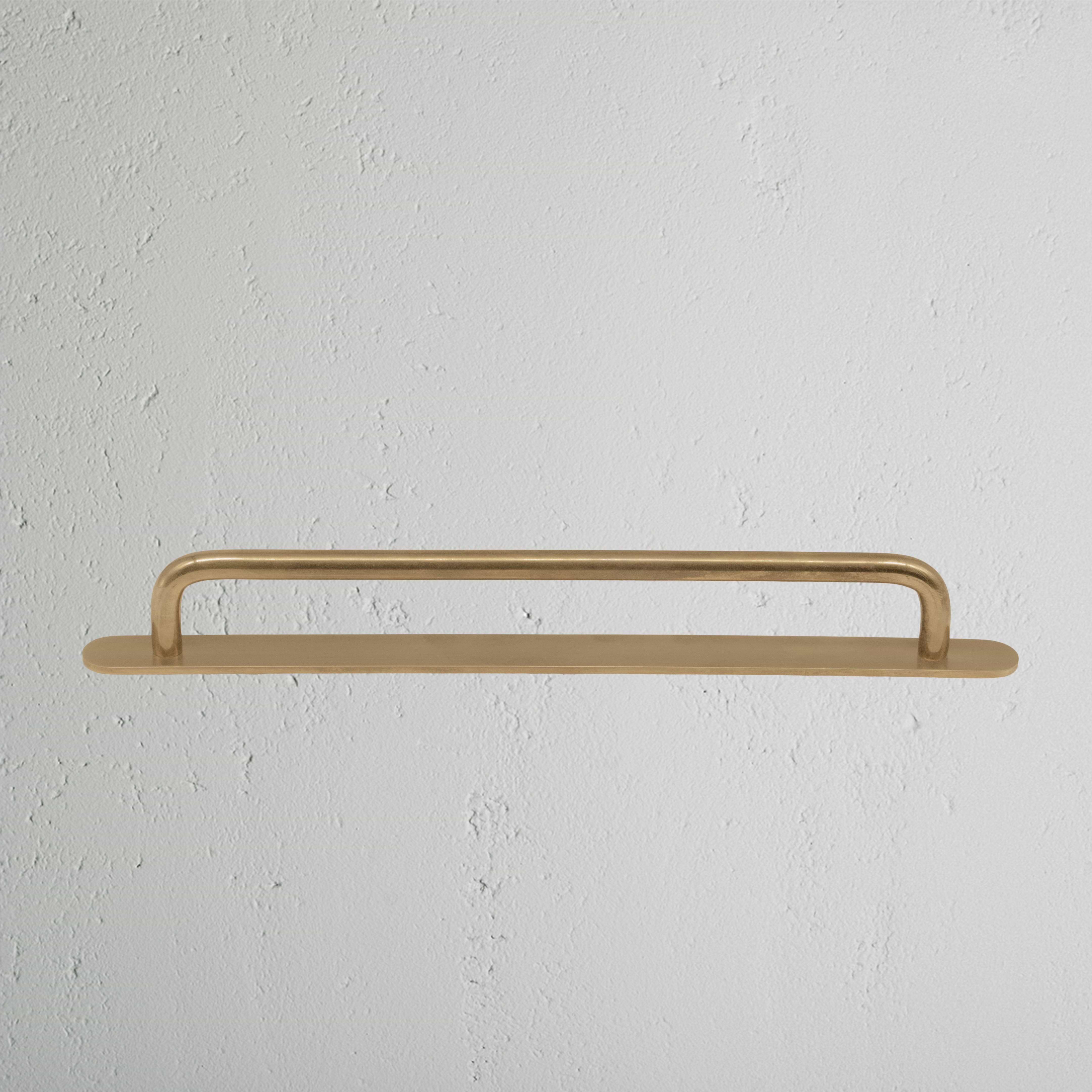 Kilburn Furniture Handle Medium in Antique Brass finish, mounted on a white surface.