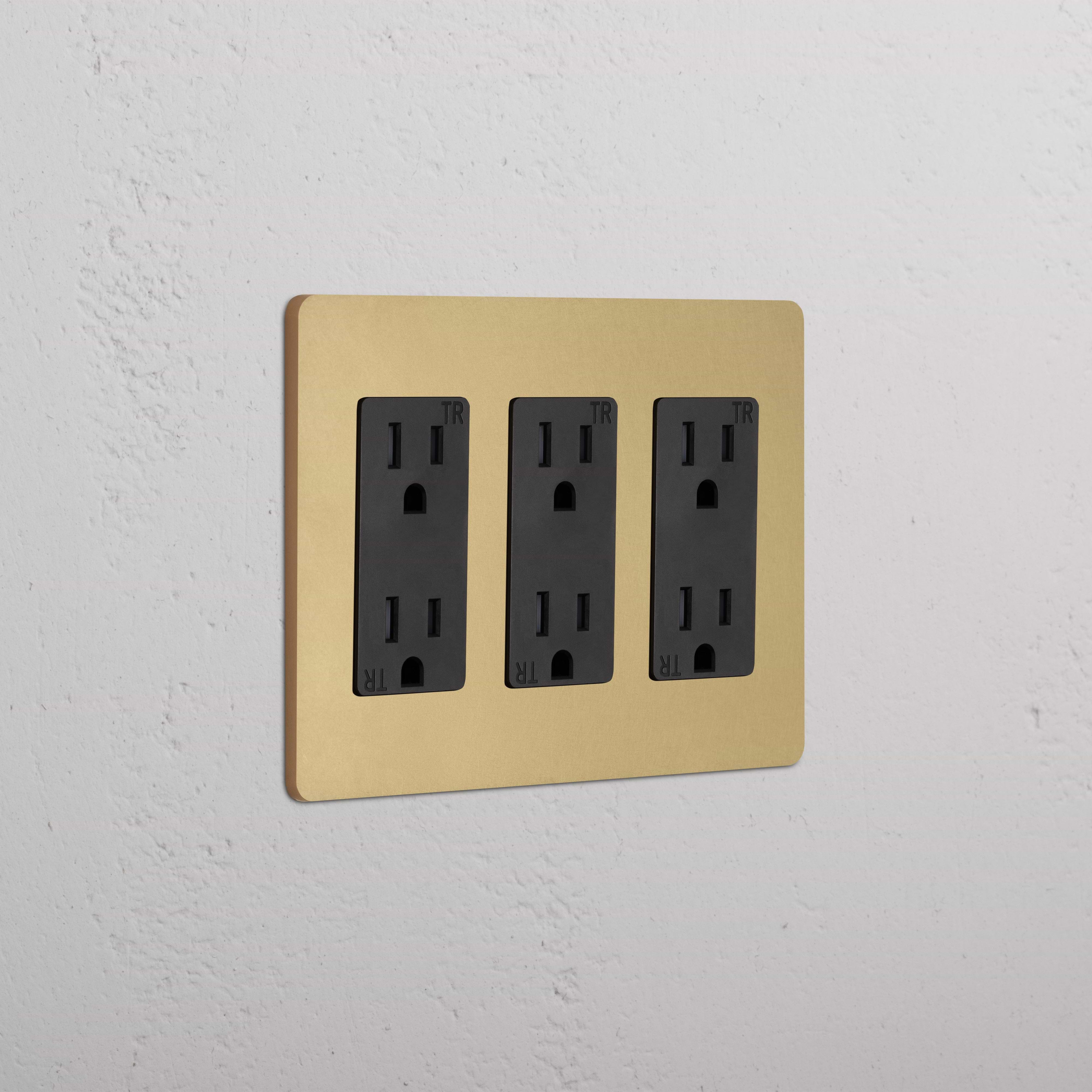 Grove 3G Outlet in Antique Brass Black with three black electrical outlets, mounted on a white wall.