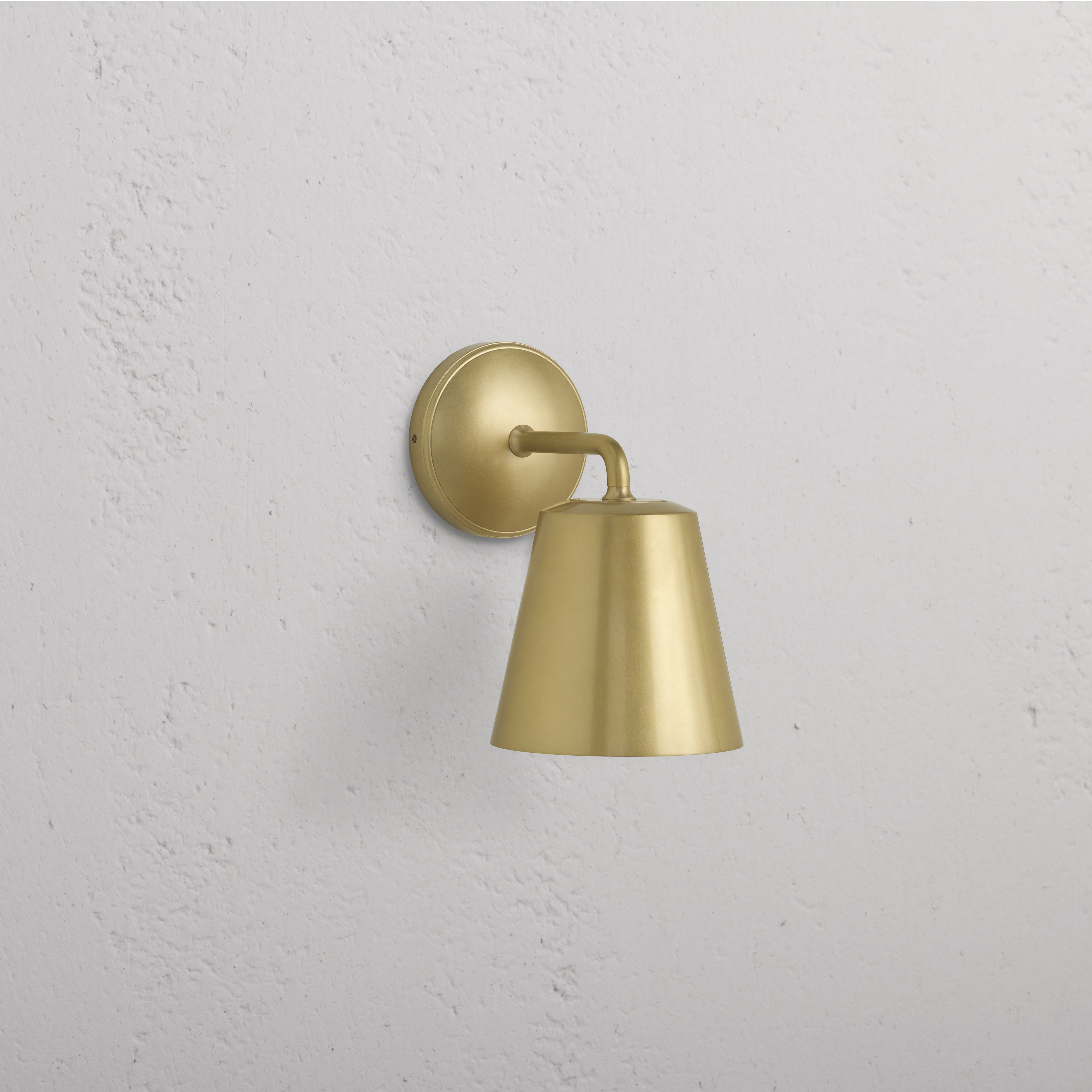 Richmond Medium Wall Light in Antique Brass with round base and conical shade, mounted on a white wall.