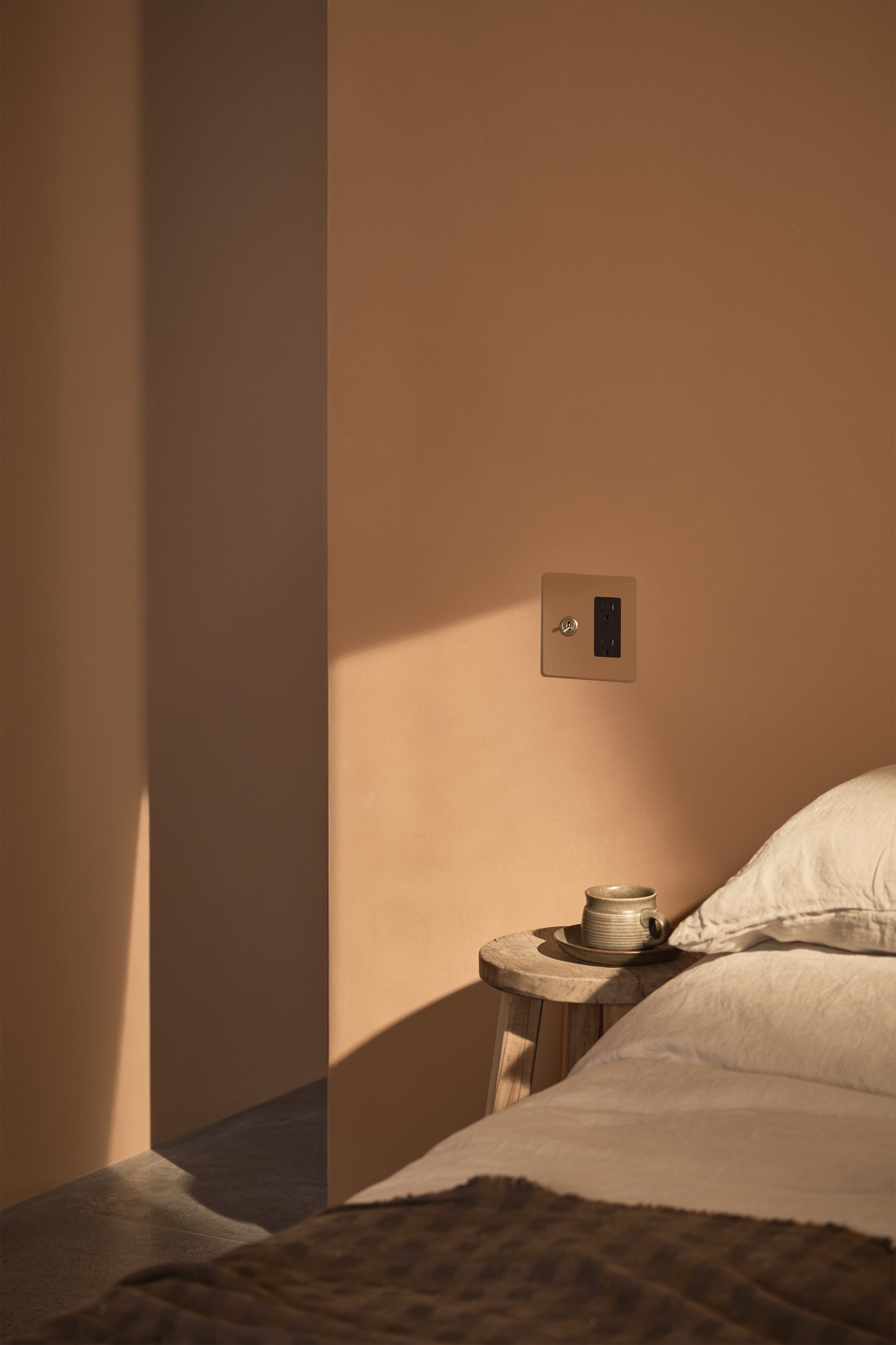 Kew 2G Toggle Switch & Outlet in Paintable Antique Brass Black mounted on a wall.