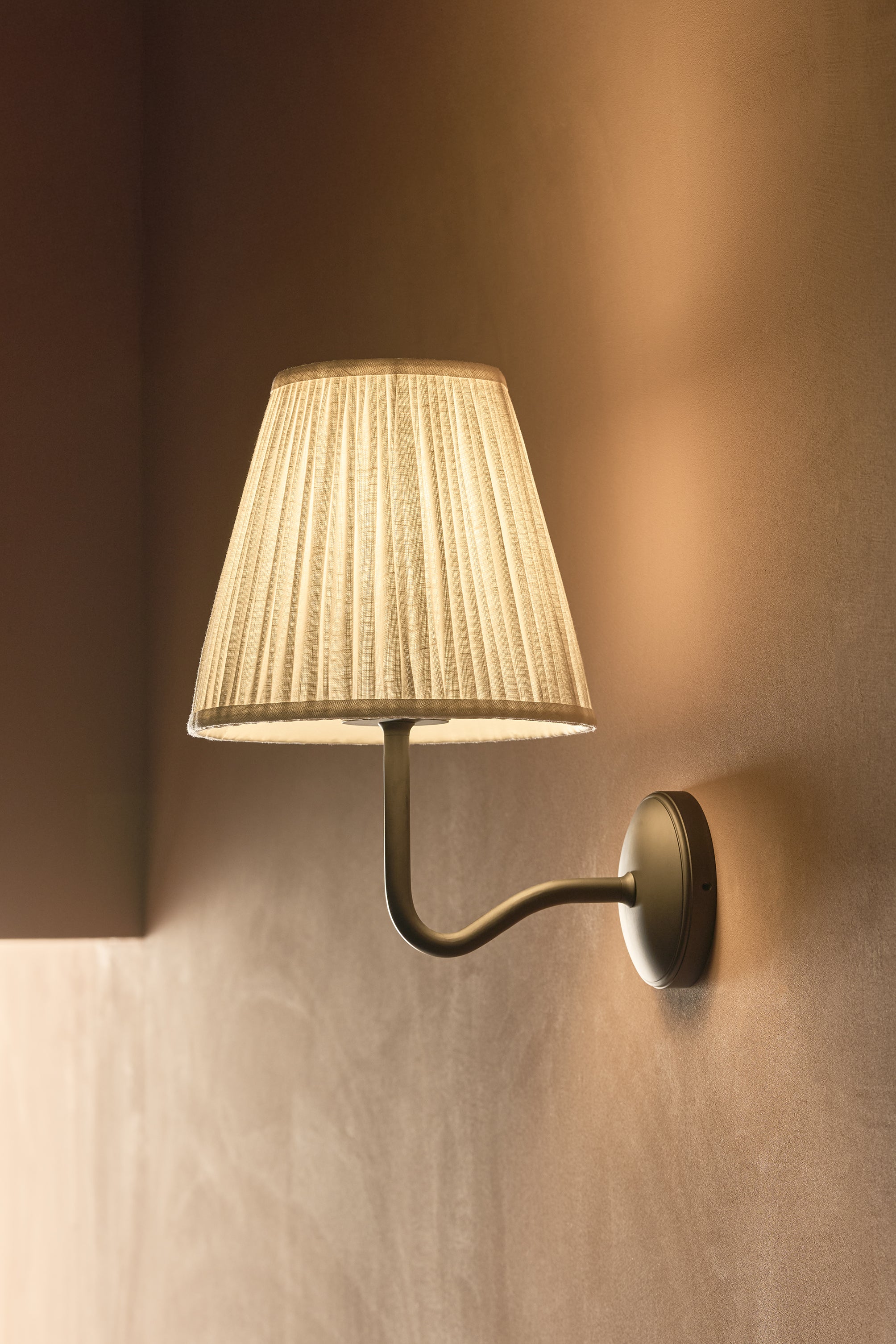 Large Malvern Wall Light in Alabaster White with bronze accents and pleated cream lampshade, mounted on wall.