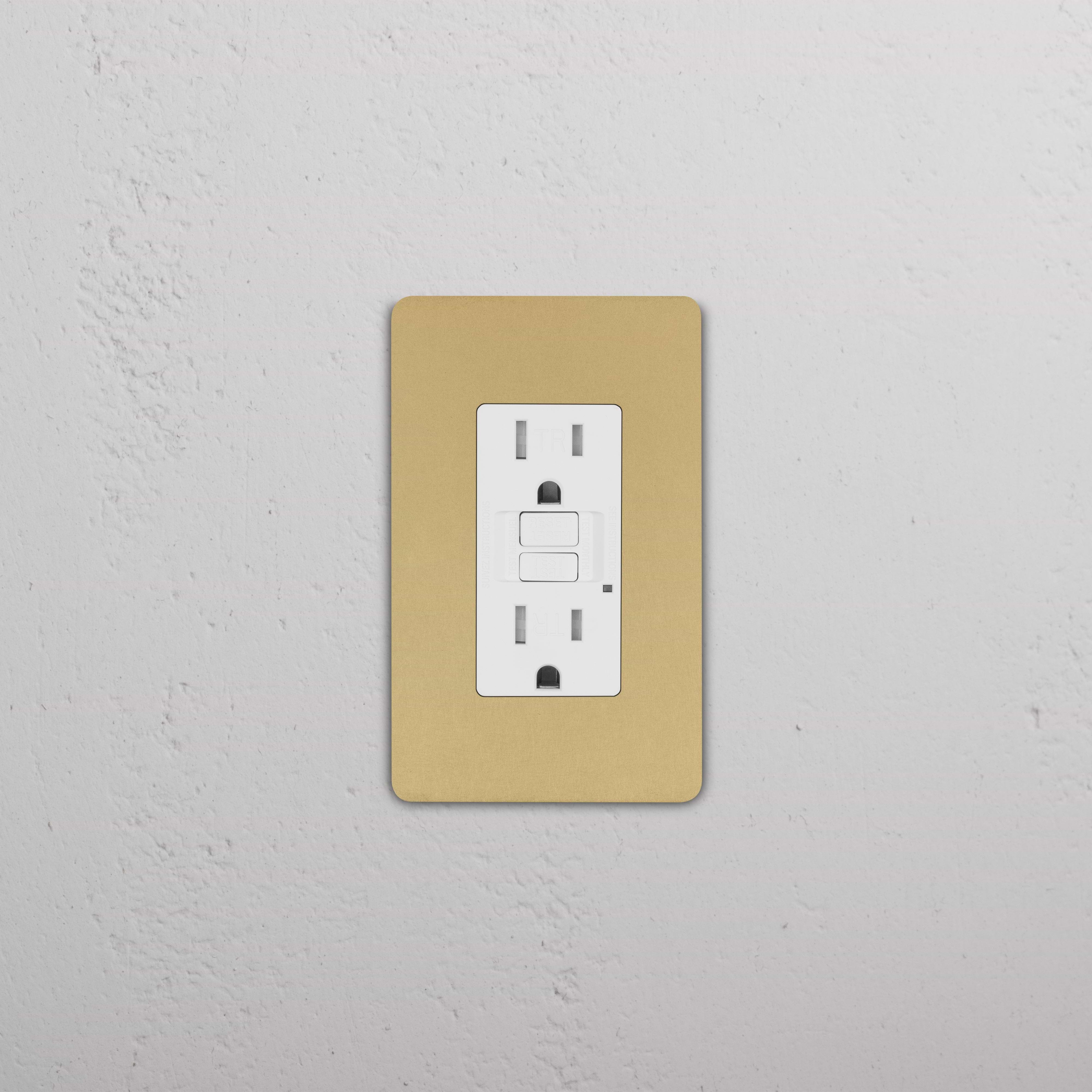 Grove 1G 15A GFCI Outlet in Antique Brass White with cover plate, shown installed on a white wall.