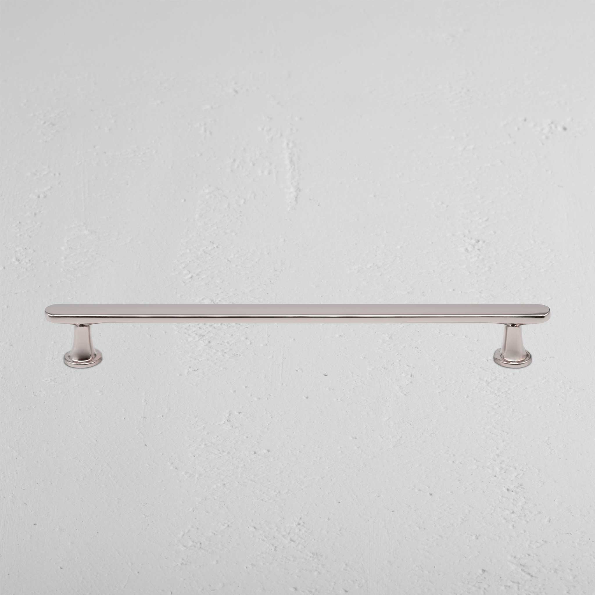 Milliner Furniture Handle Medium in polished nickel with two round bases, mounted on a white wall.