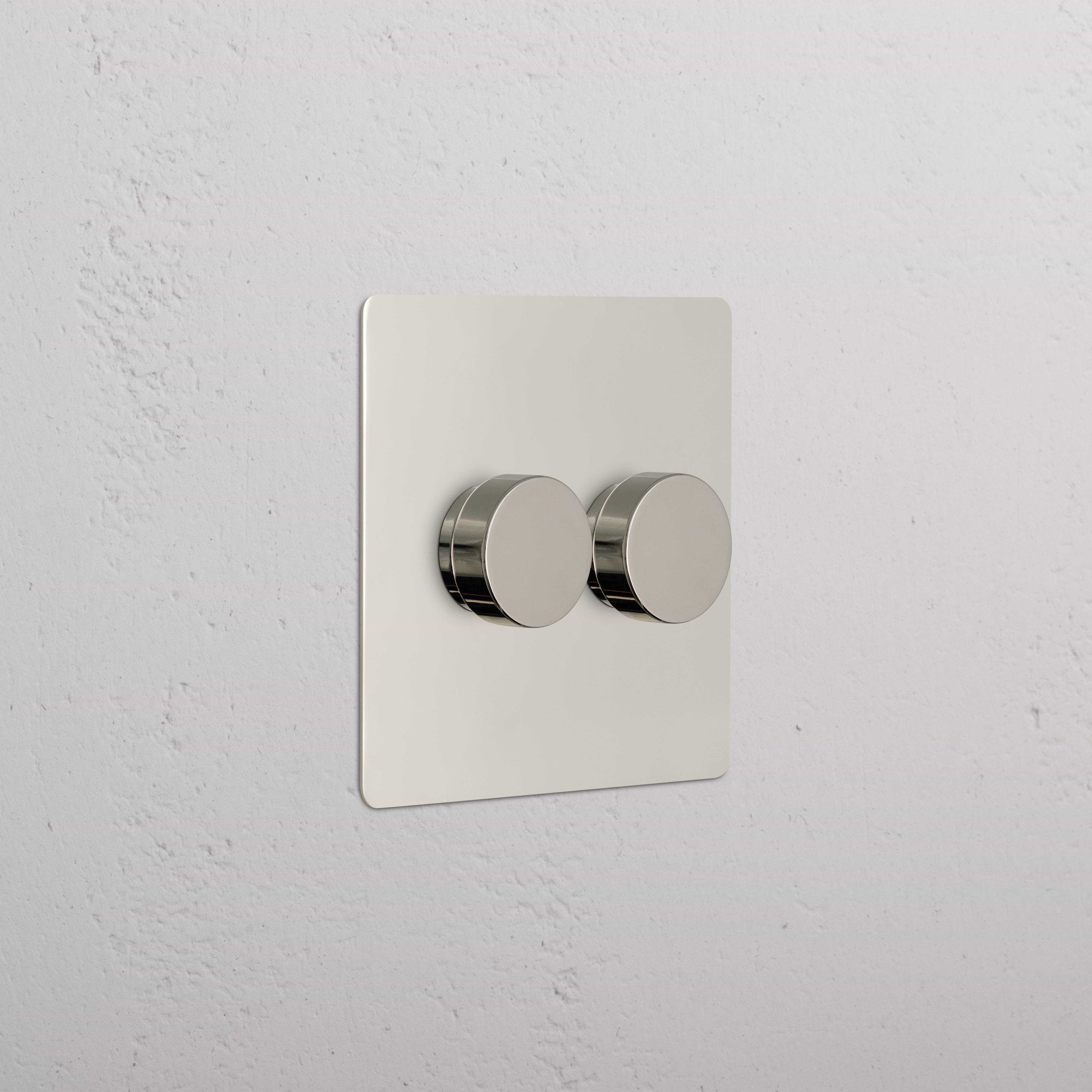 Kew 2G Dimmer Switch in polished nickel with two round knobs on a square plate, mounted on a wall.