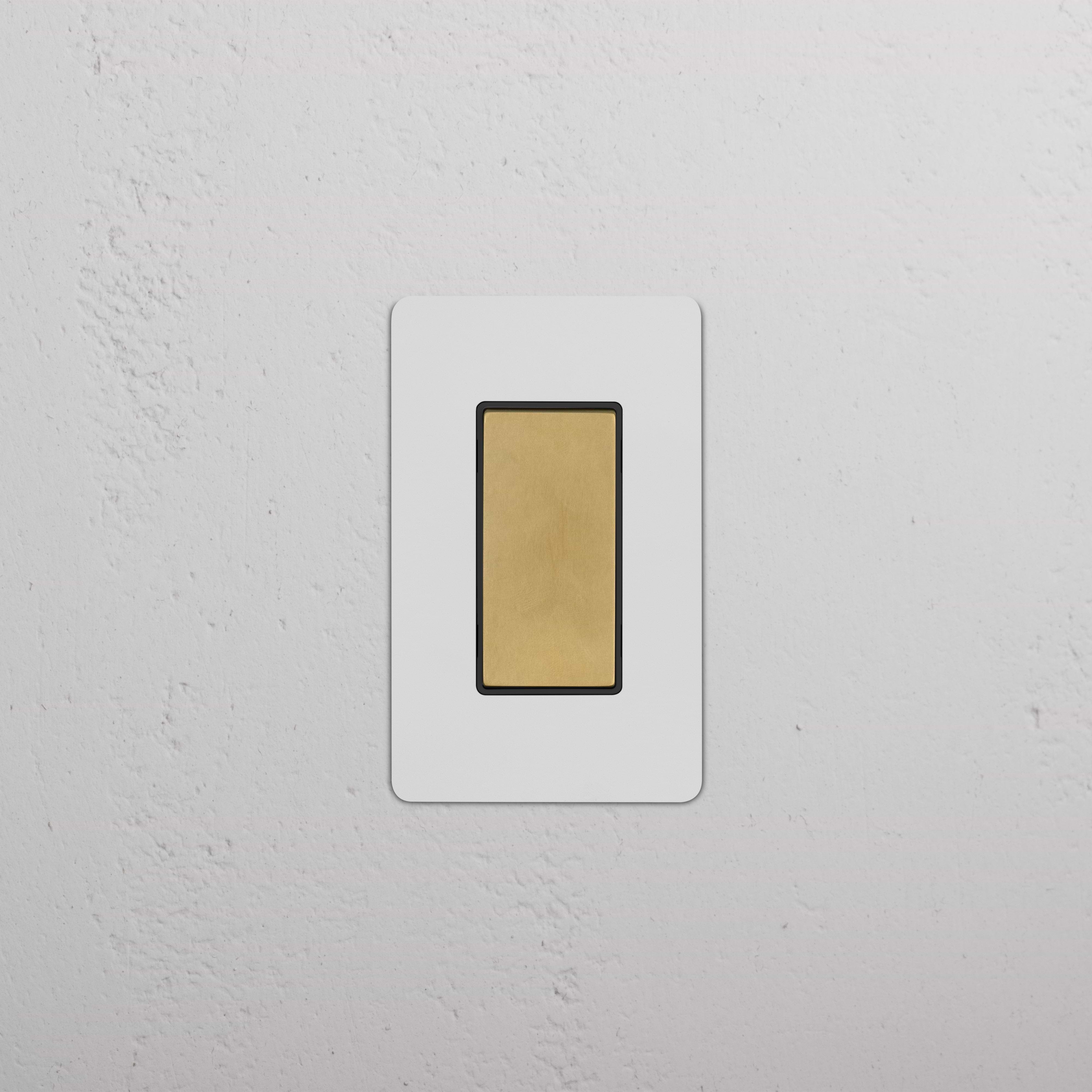 Kew 1G Center Retractive Rocker Switch in paintable antique brass black, shown on a textured white wall.