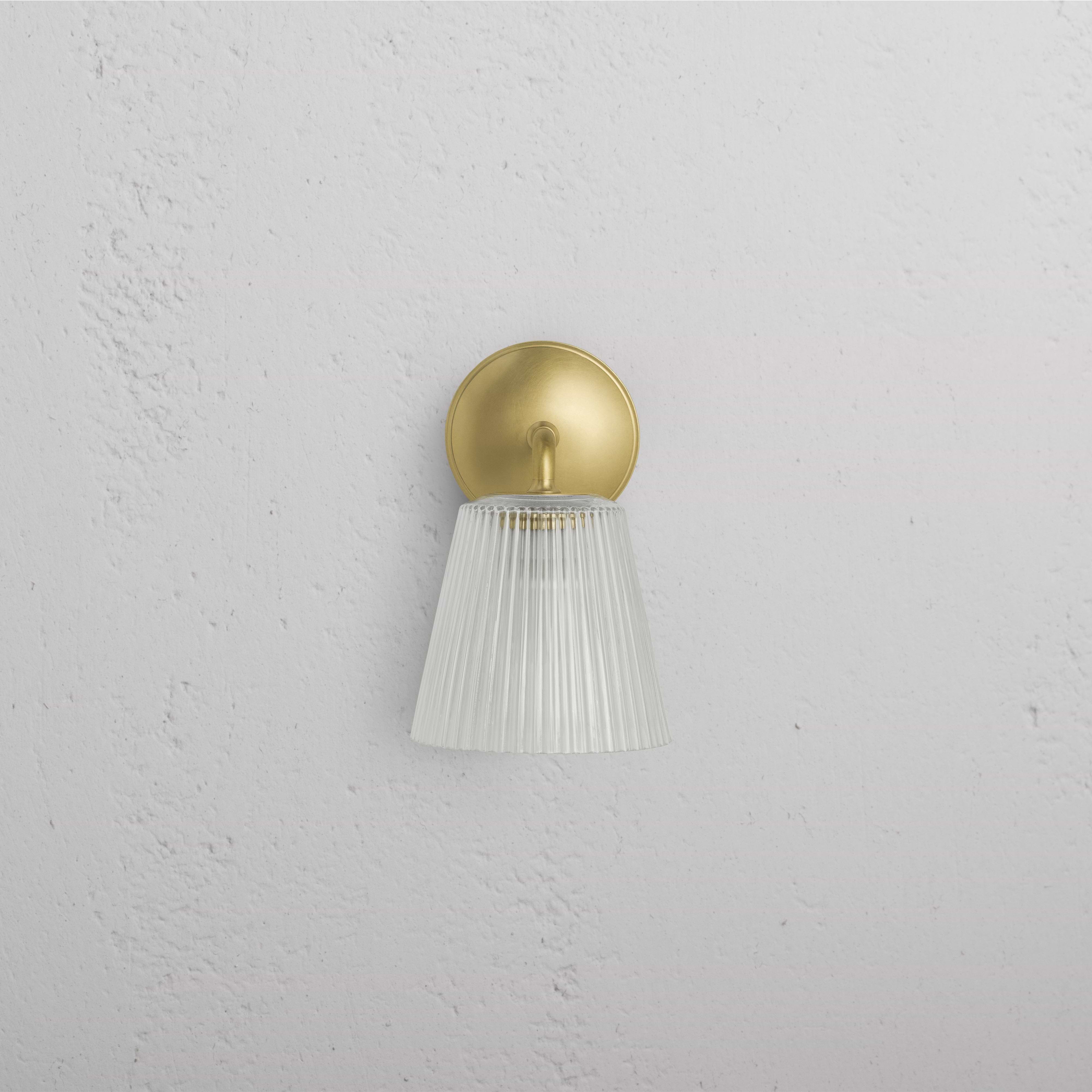 Richmond Medium Wall Light with fluted glass shade and antique brass base, mounted on a white wall.