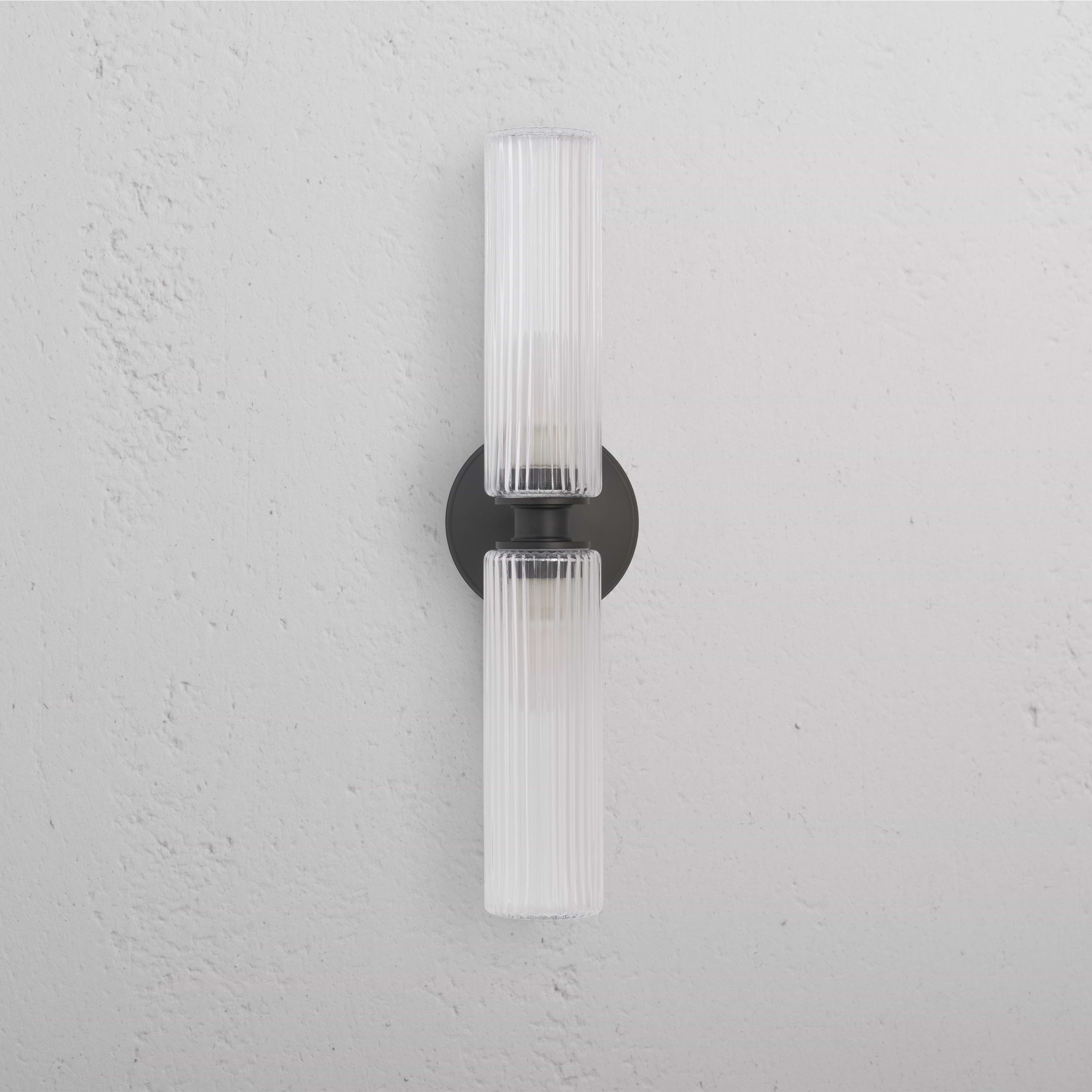 Claremont Medium Wall Light with fluted glass and bronze round base, mounted on a white wall.