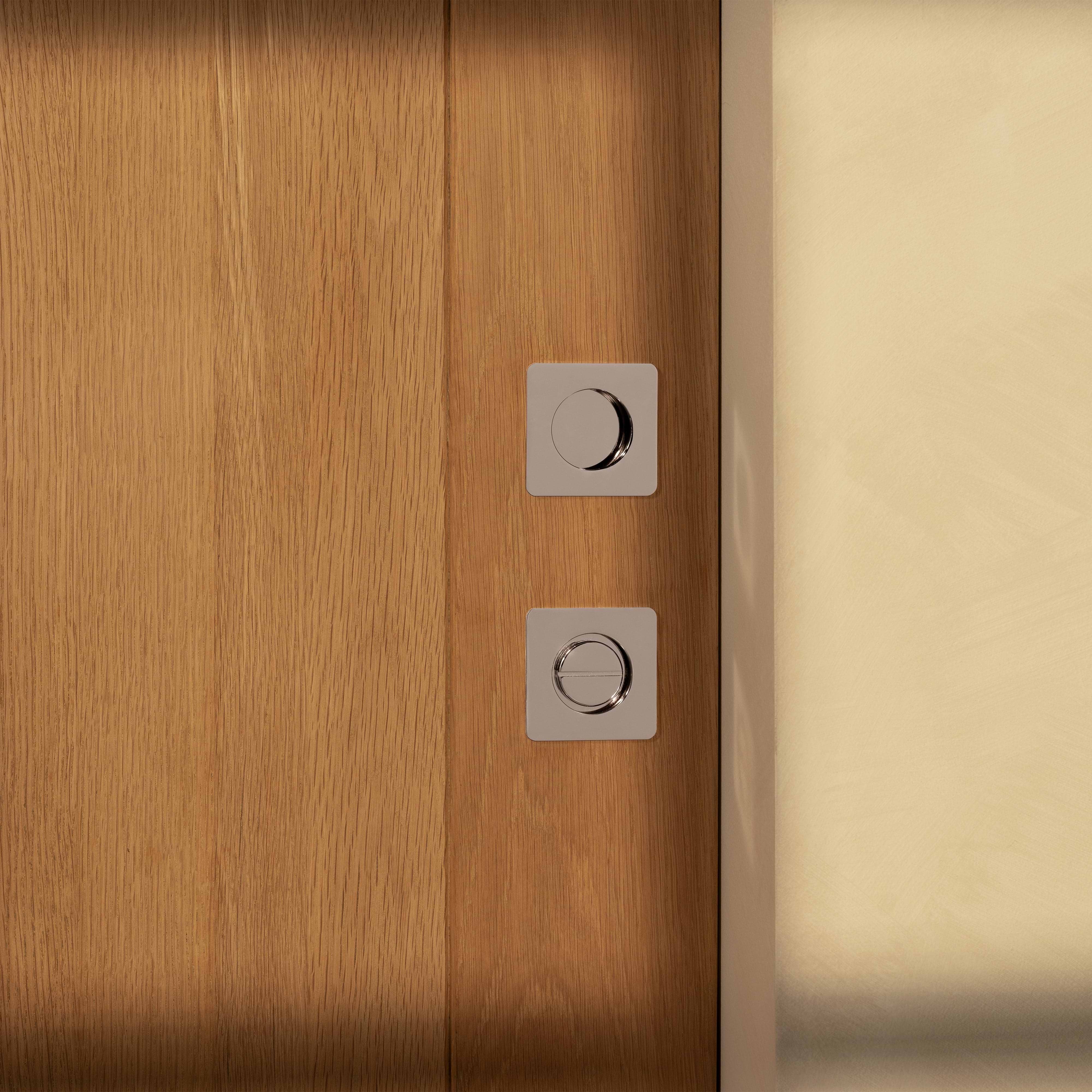 Regent Recessed Thumbturn in polished nickel, installed on a wooden door near a light-colored wall.