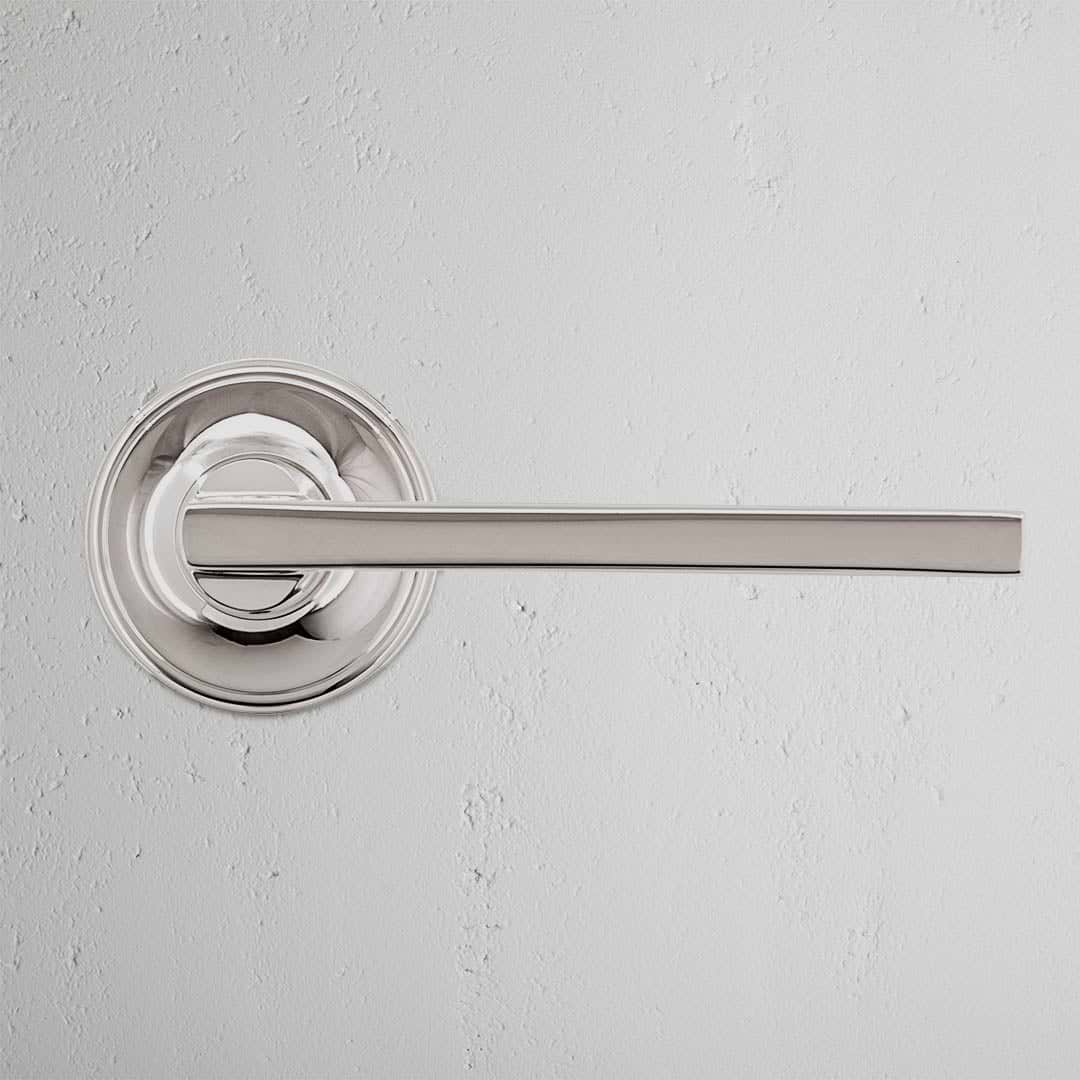 Clayton Unsprung Passage Door Handle Set in polished nickel with circular base, mounted on a light wall.