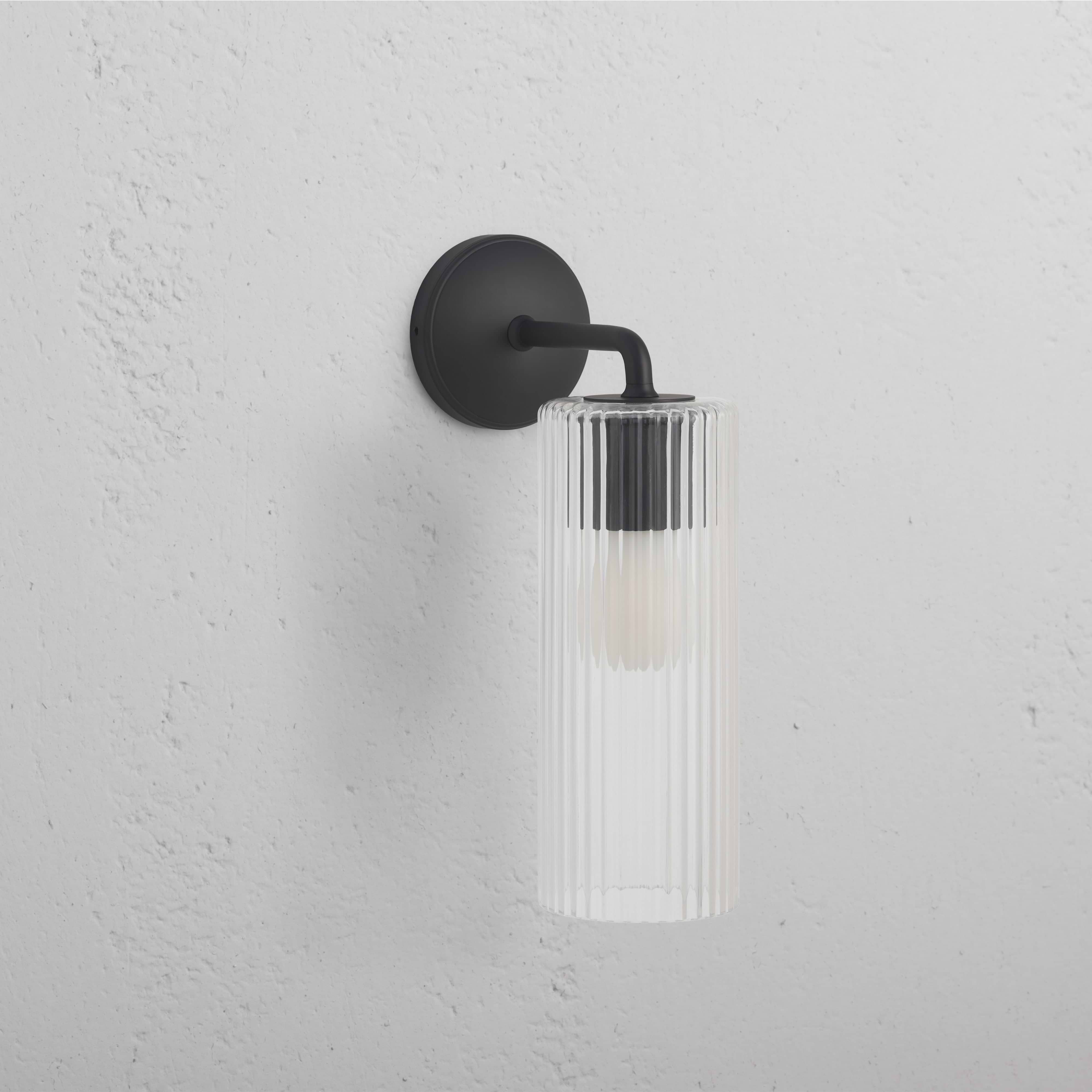 Large Claremont Wall Light Fluted Glass in bronze finish, with vertically fluted glass shade on a wall.