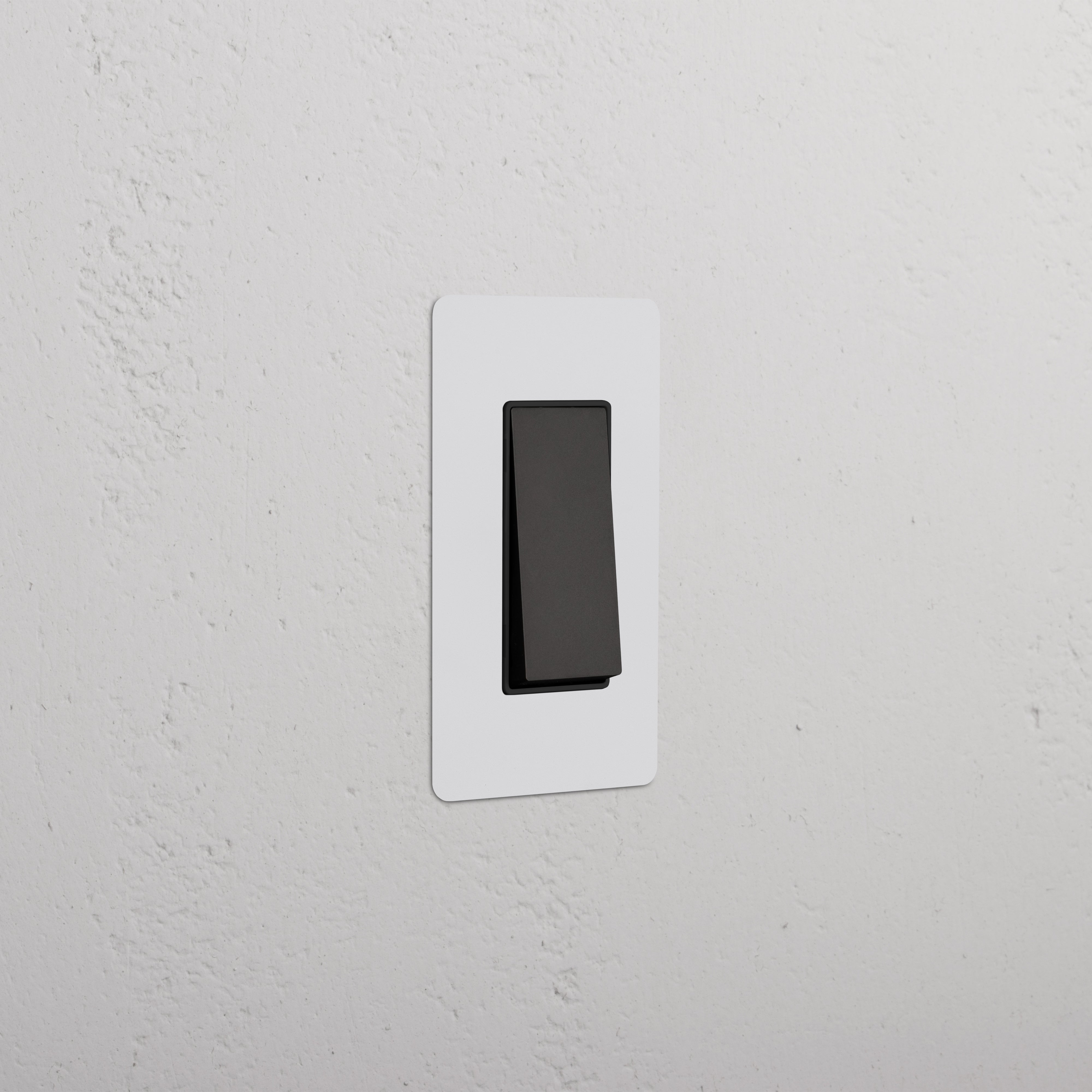 Kew 1G Double Pole Rocker Switch in paintable bronze black finish, mounted on a wall.