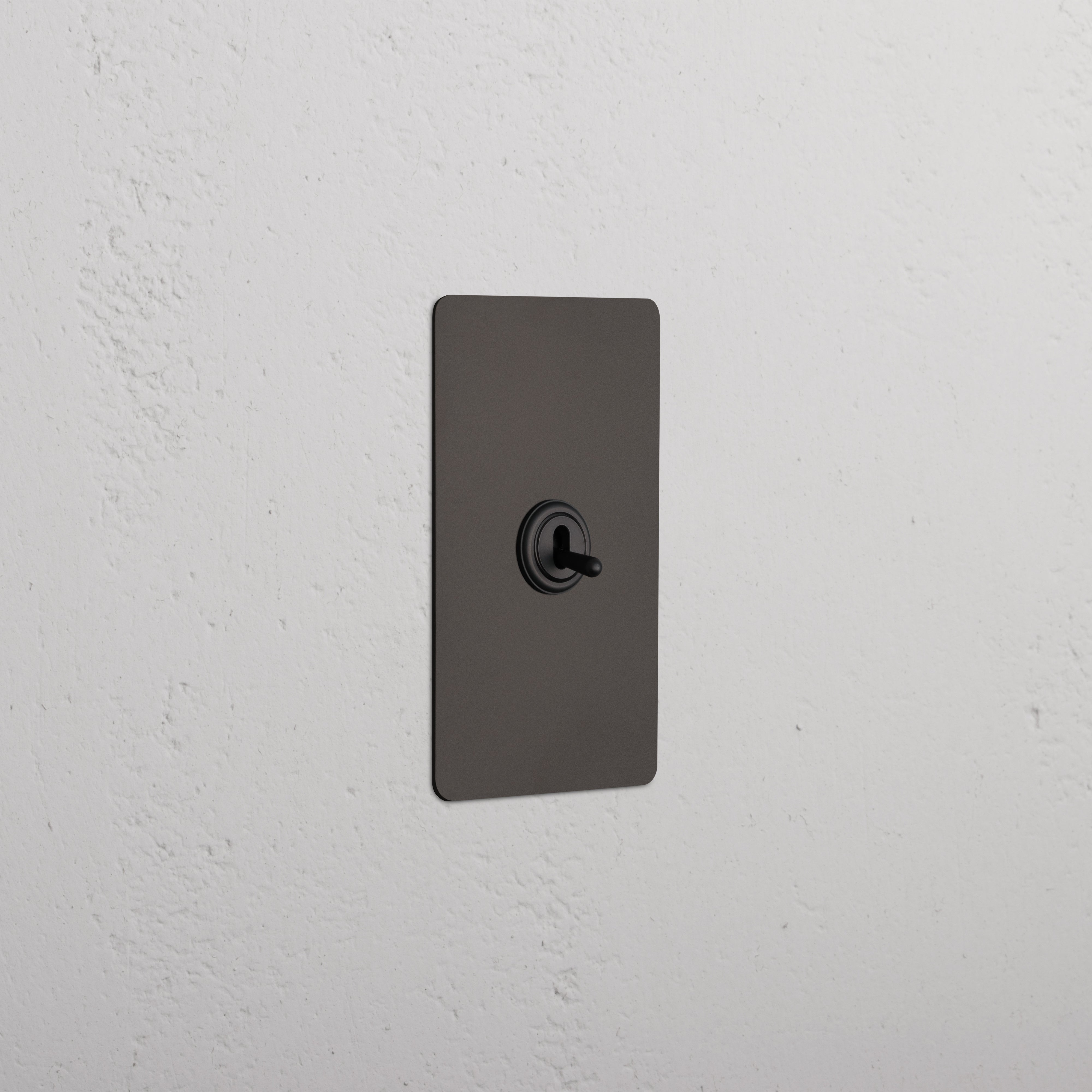 Kew 1G Retractive Toggle Switch in bronze finish with black toggle, mounted on a white textured wall.