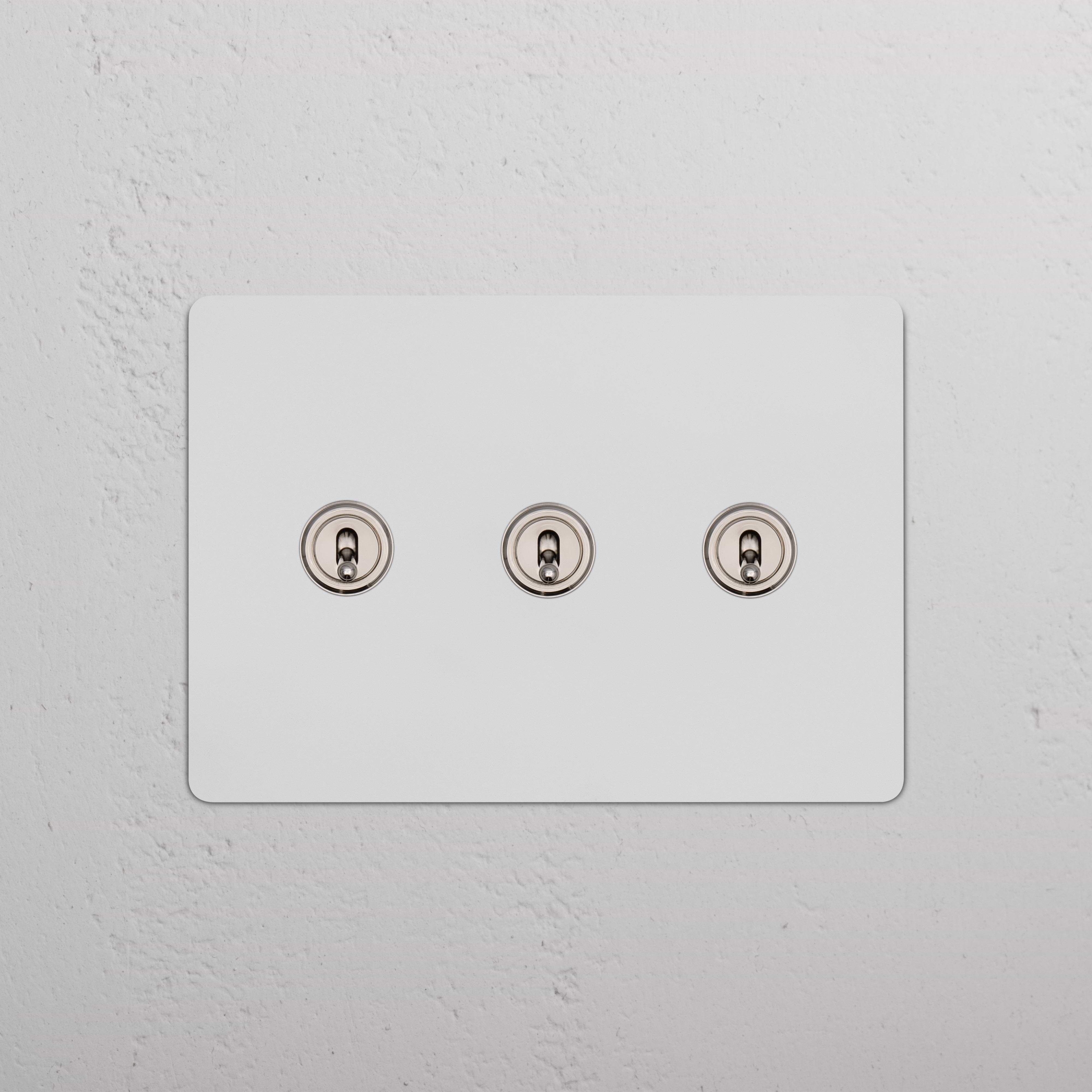 Kew 3G Toggle Switch in paintable polished nickel with three horizontal toggles on a wall plate.