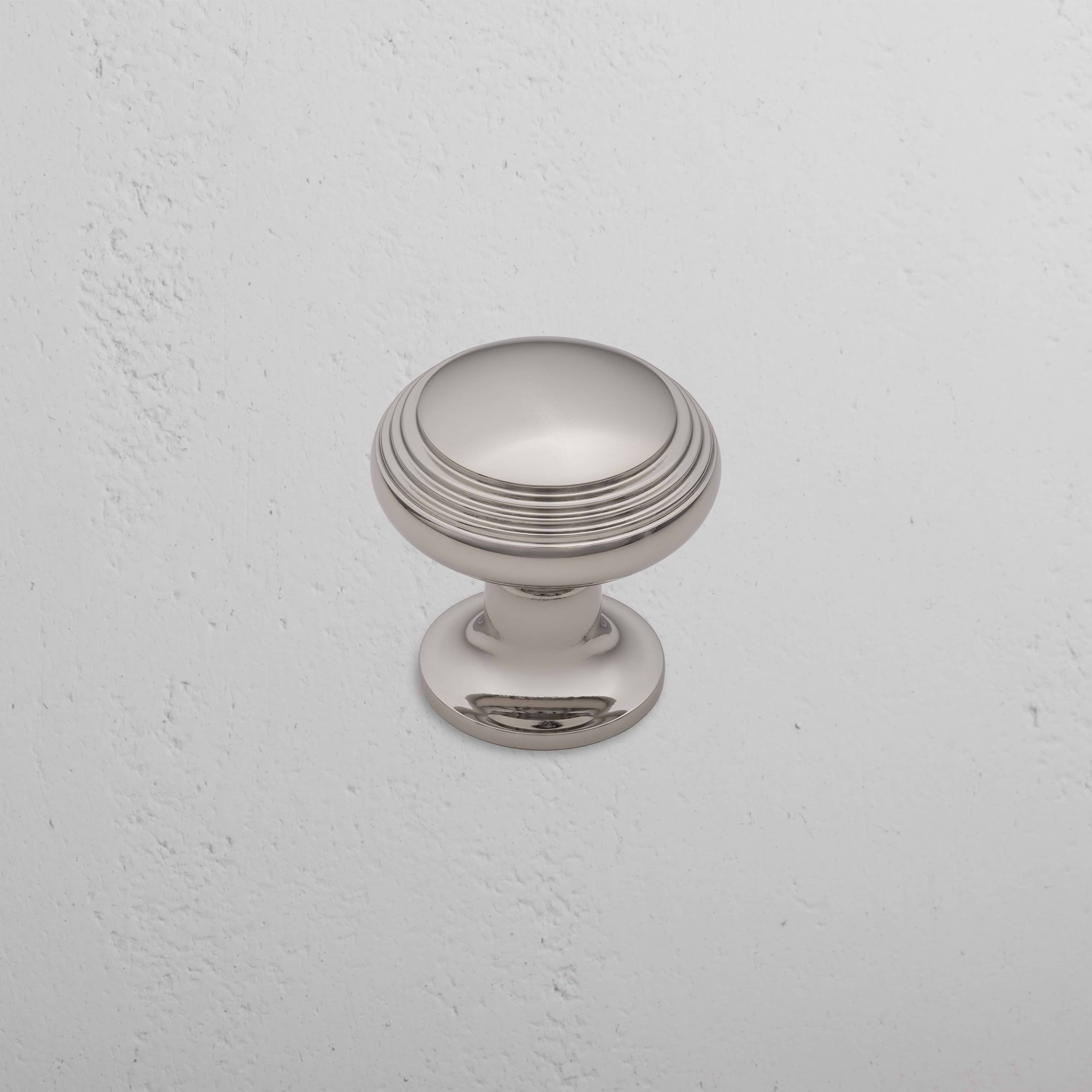 Barlow Furniture Knob Medium in polished nickel with subtle grooves, shown mounted on a white wall.