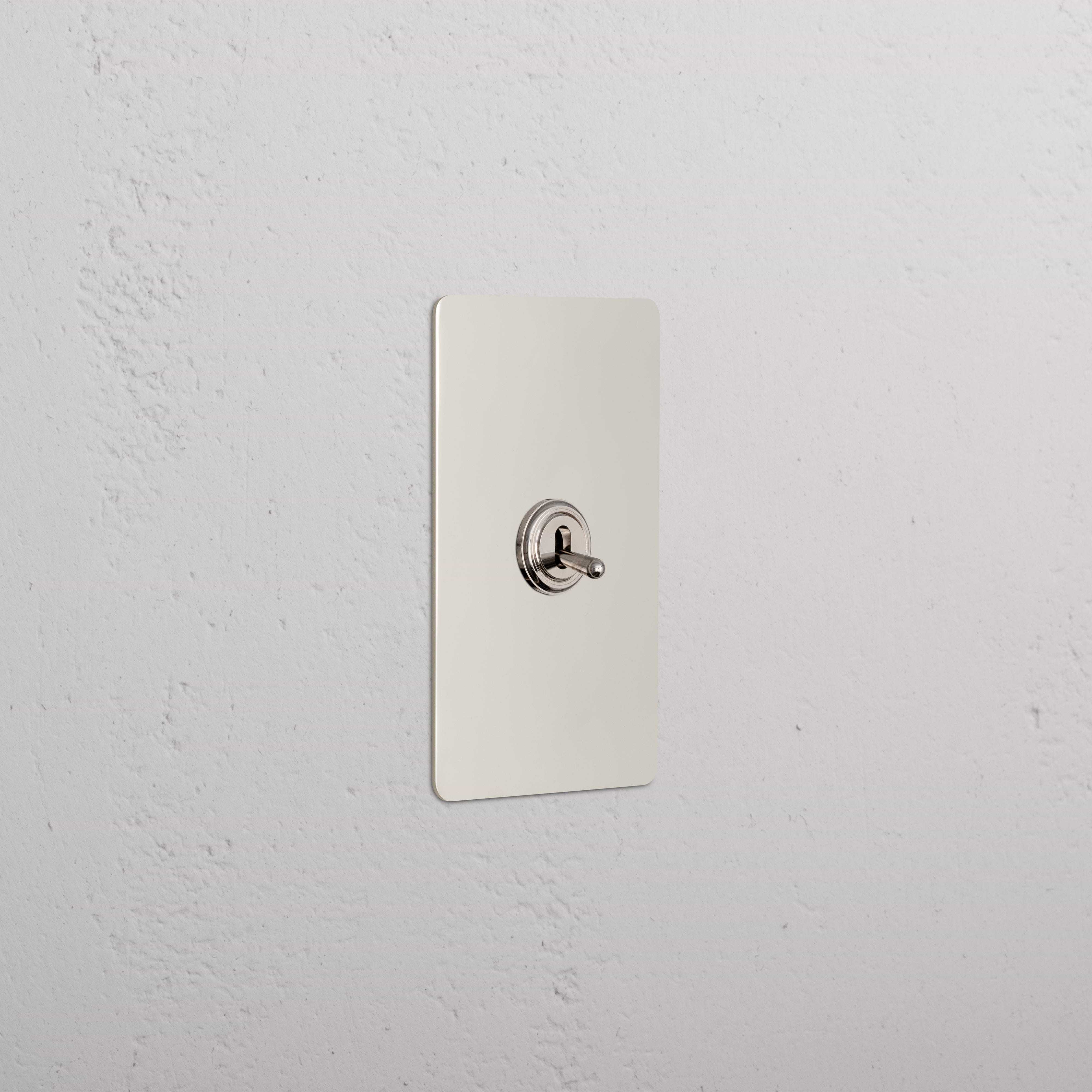 Kew 1G Toggle Switch in polished nickel with a rectangular plate and rounded corners, mounted on a wall.