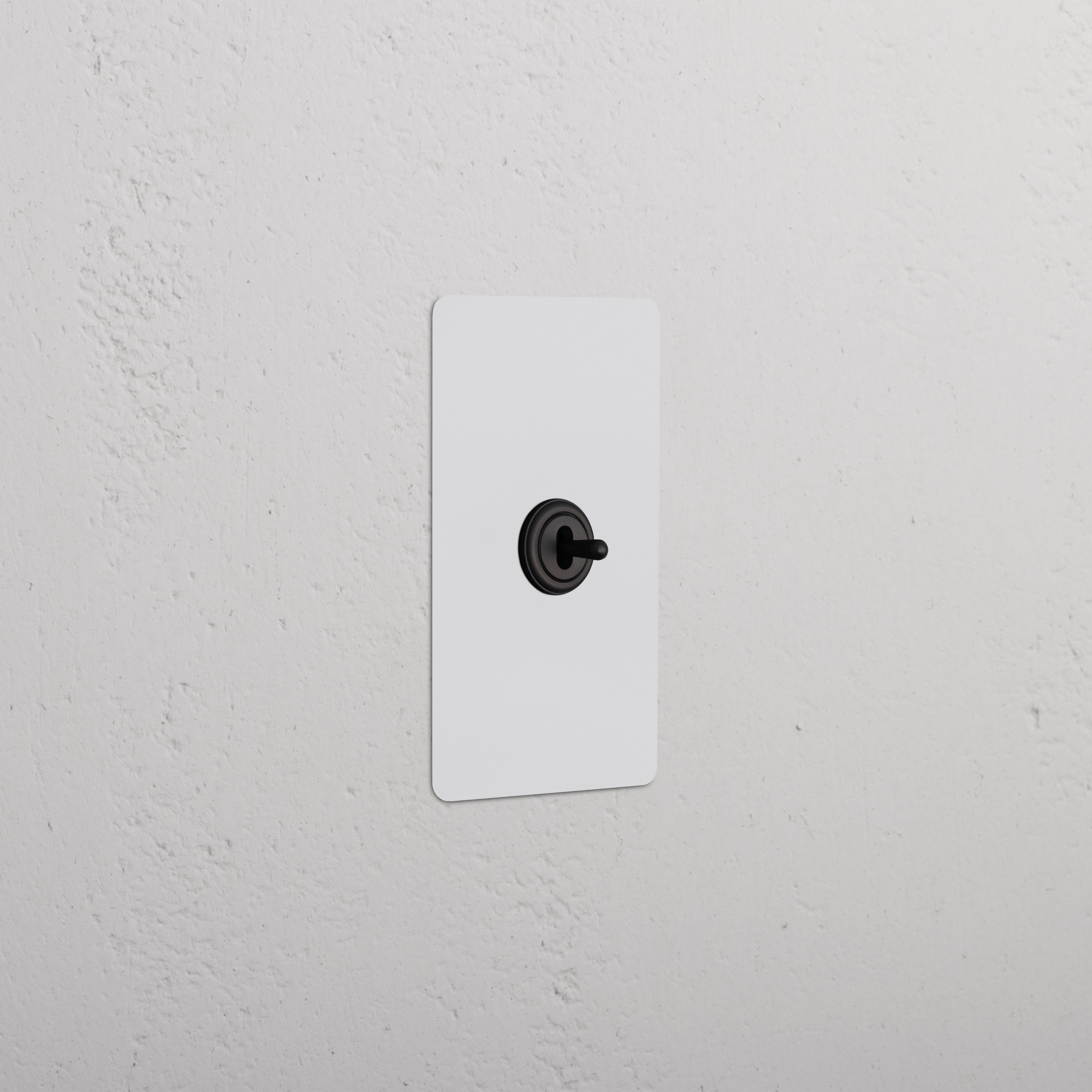 Kew 1G Center Retractive Toggle Switch in paintable bronze finish, single gang, on a white wall.