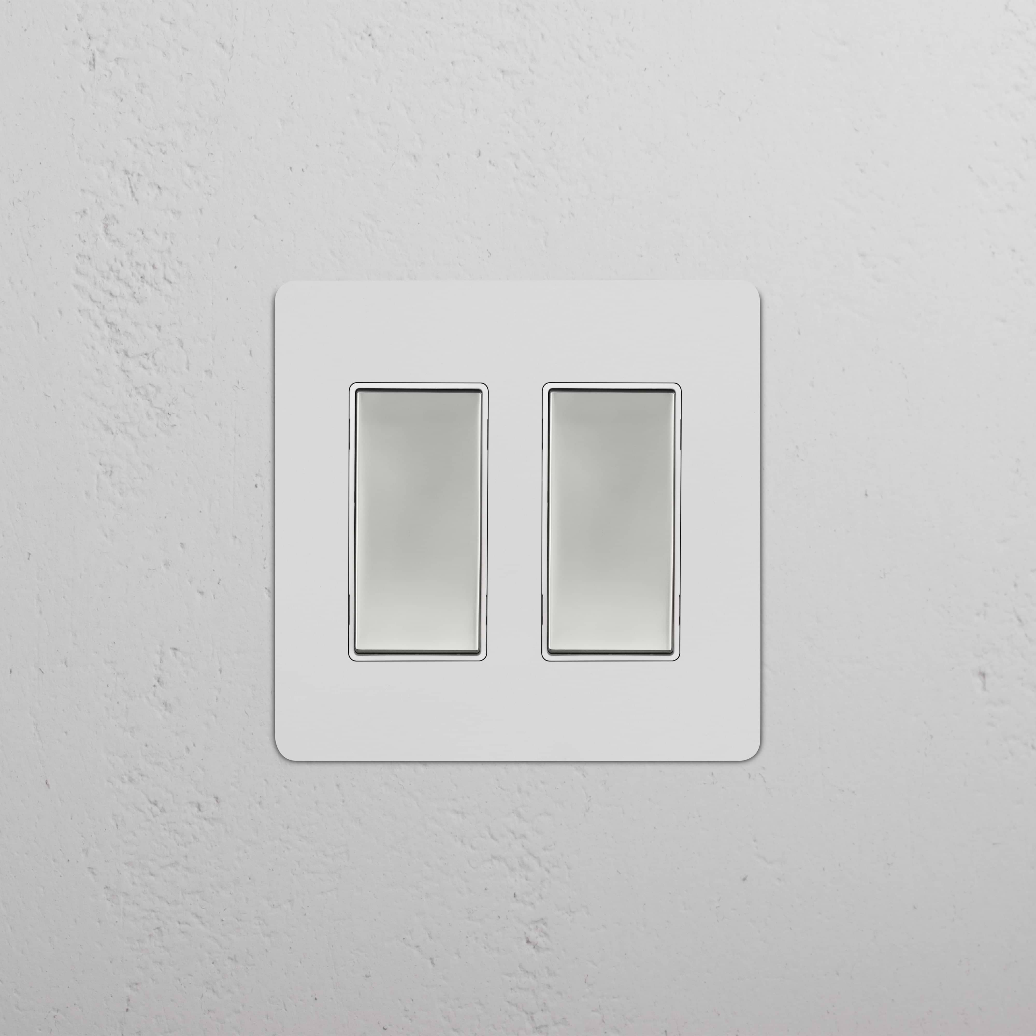 Kew 2G Rocker Switch in paintable polished nickel white finish, both switches shown off on a white wall.