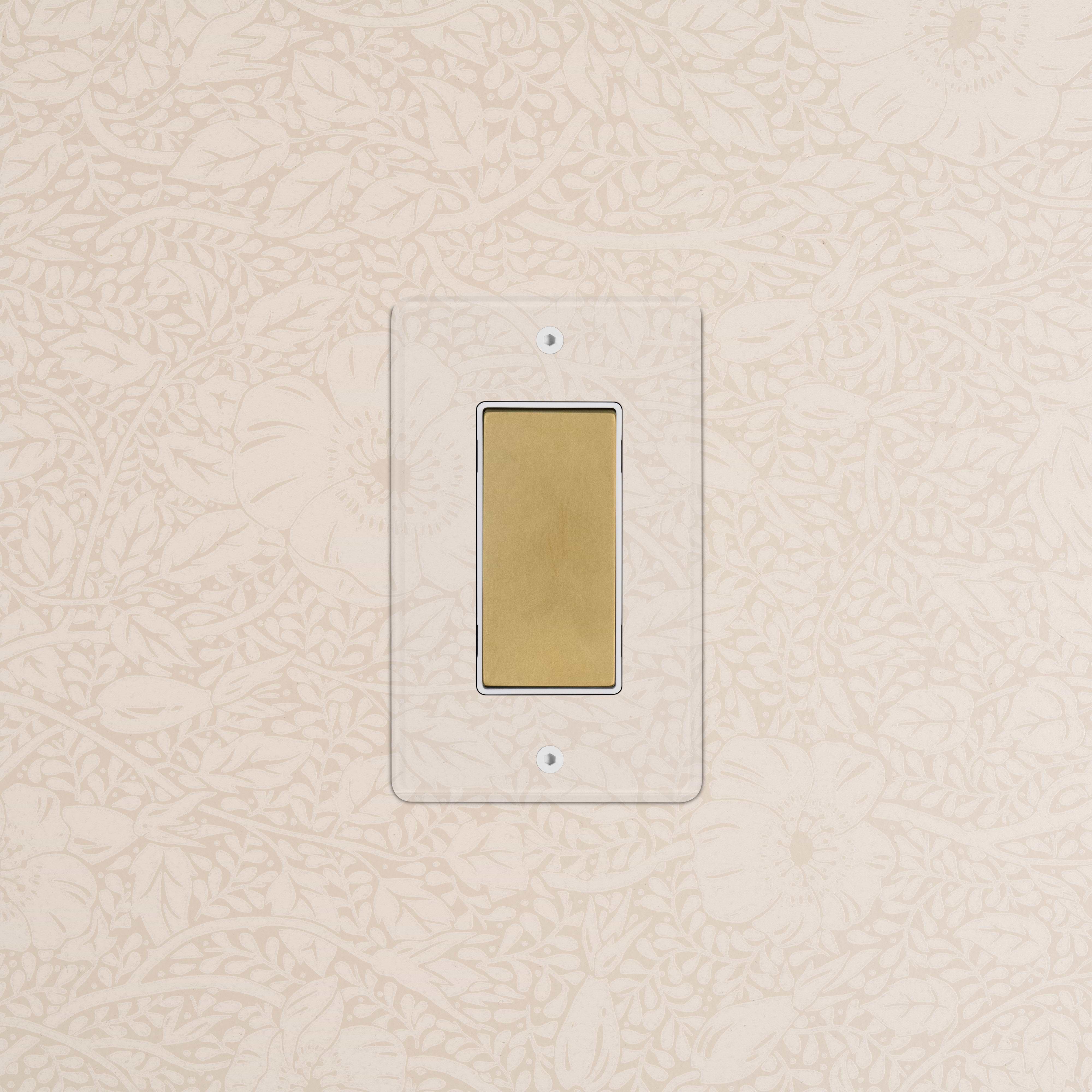Kew 1G Center Retractive Rocker Switch in clear antique brass with white rocker, mounted on wall.