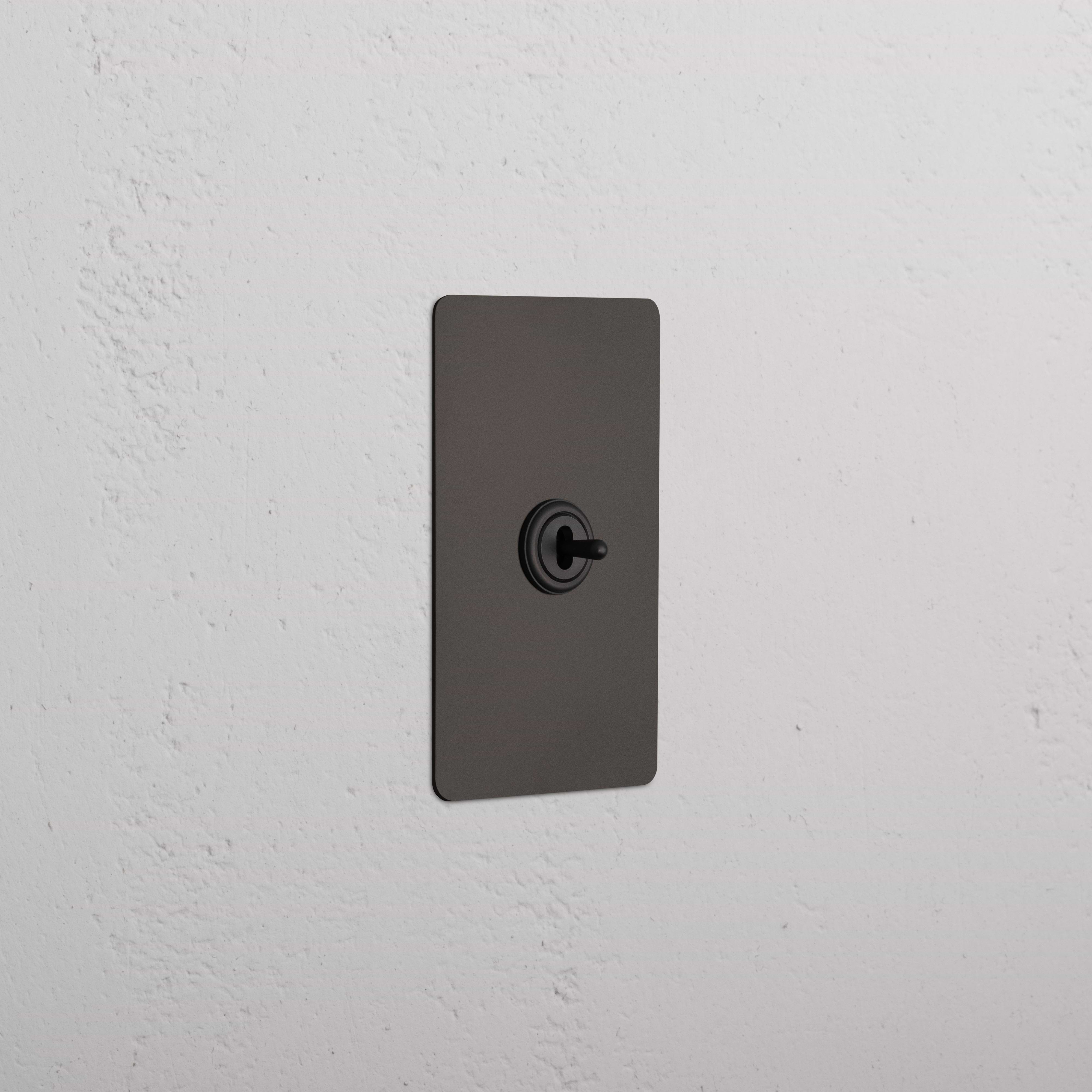 Kew 1G Center Retractive Toggle Switch in bronze finish, featuring a central circular toggle on a standard plate.