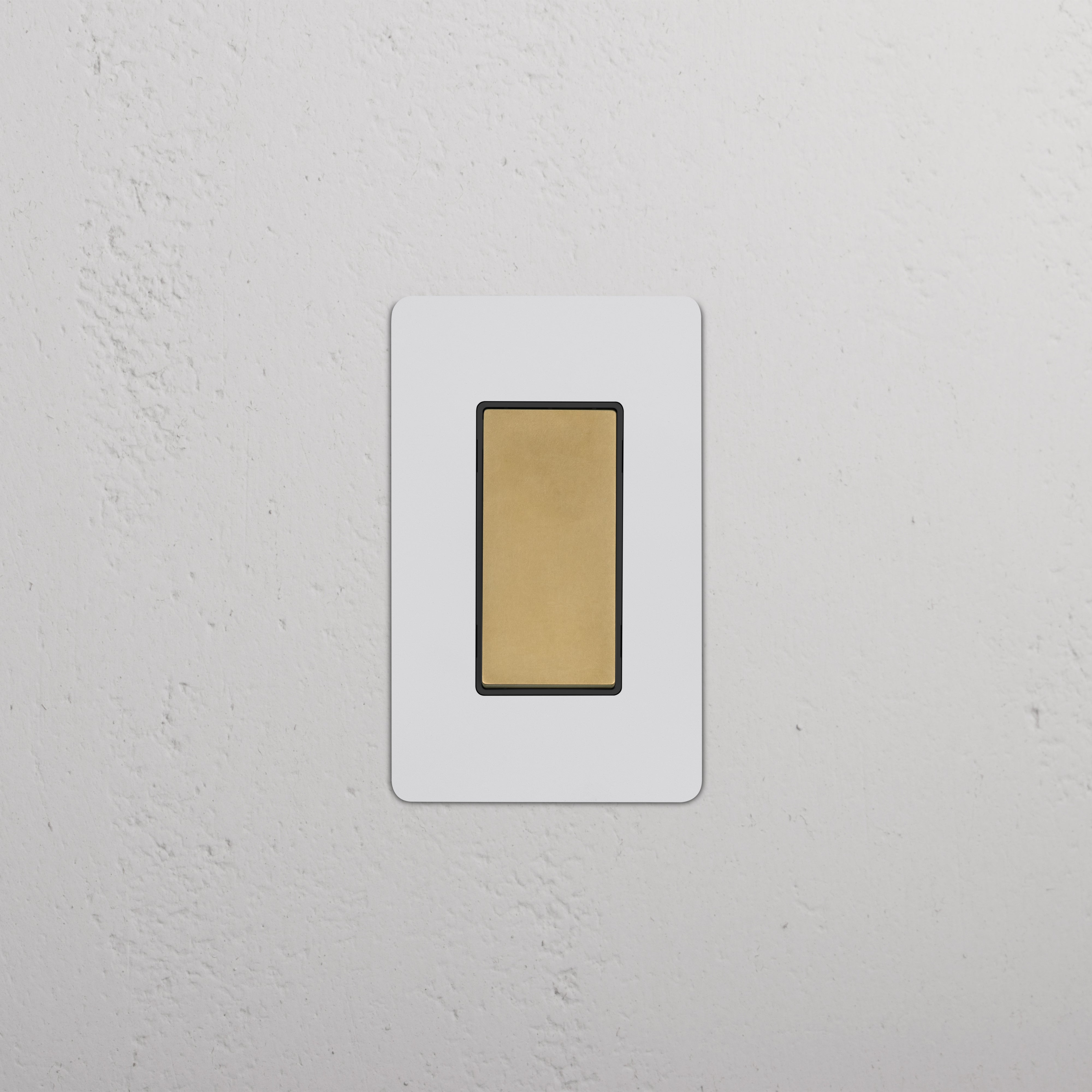 Kew 1G Retractive Rocker Switch in Paintable Antique Brass Black, shown mounted on a white wall.
