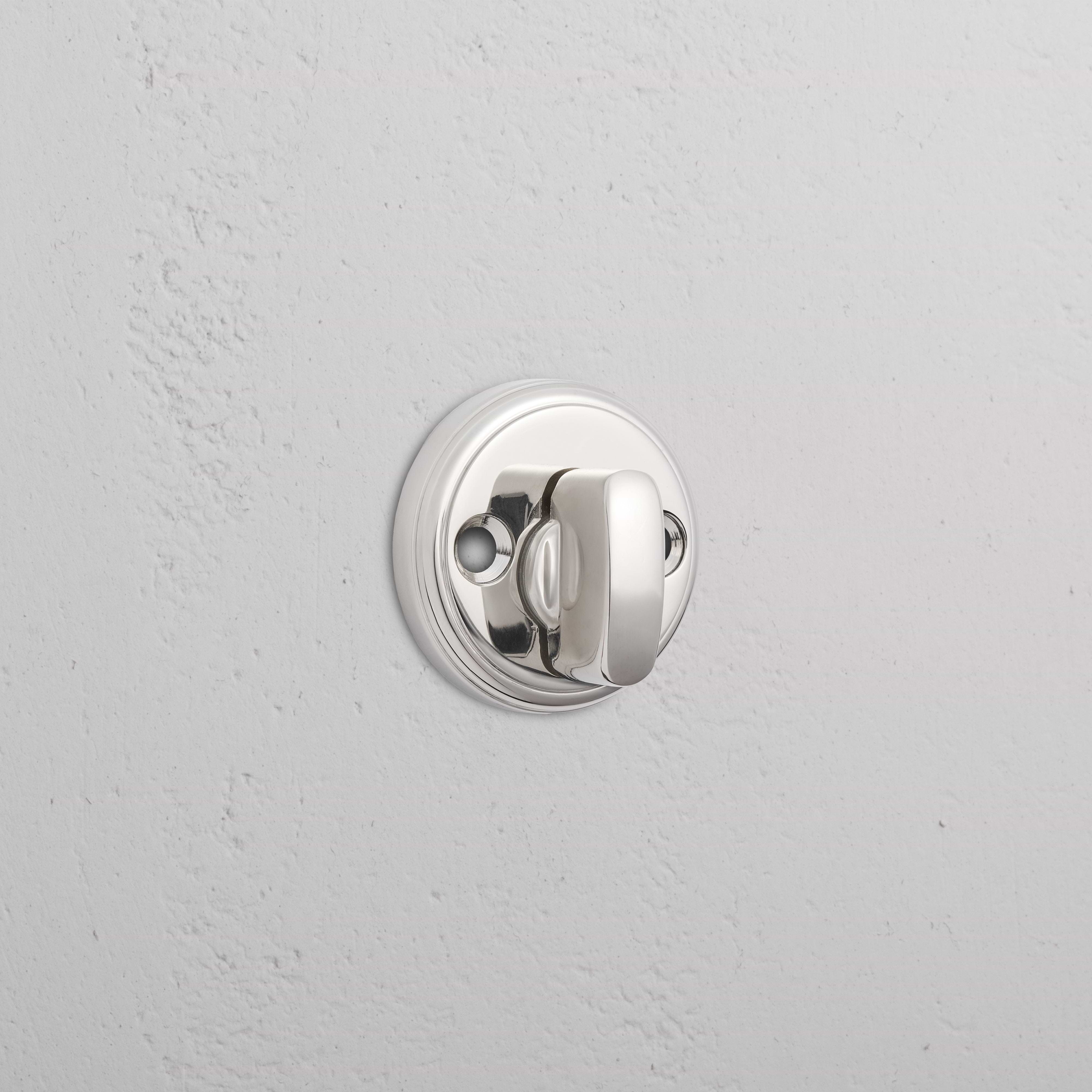 Polished nickel Canning privacy deadbolt with round design installed on a white textured door.
