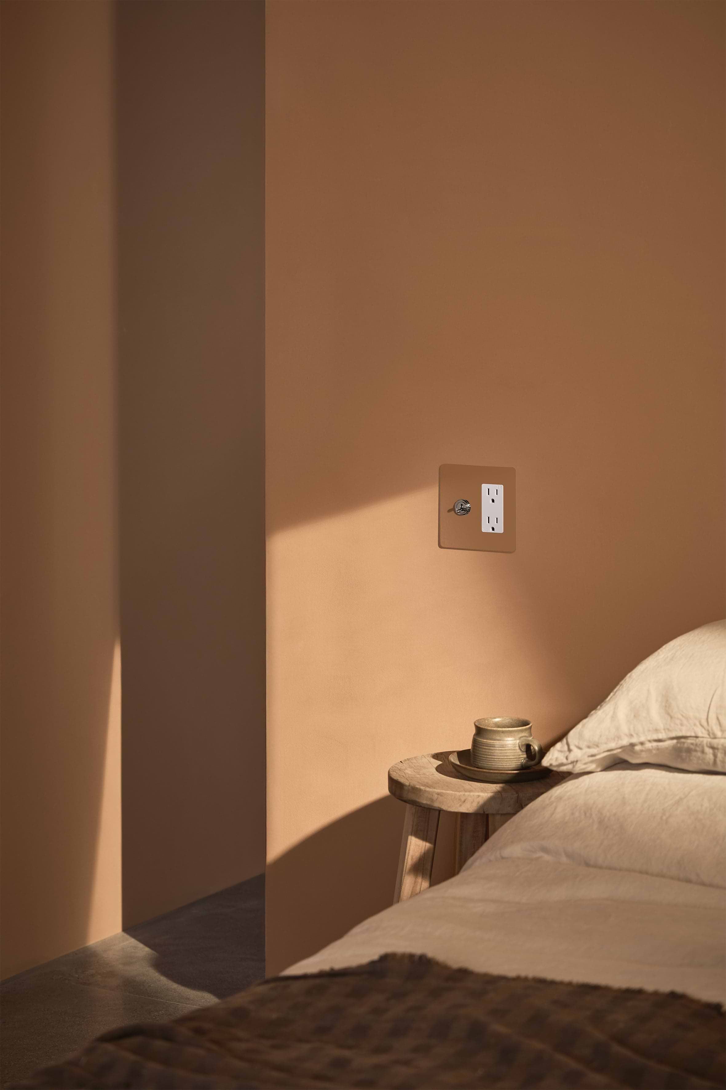 Kew 2G Toggle Switch & Outlet in paintable polished nickel white, installed on a tan wall.